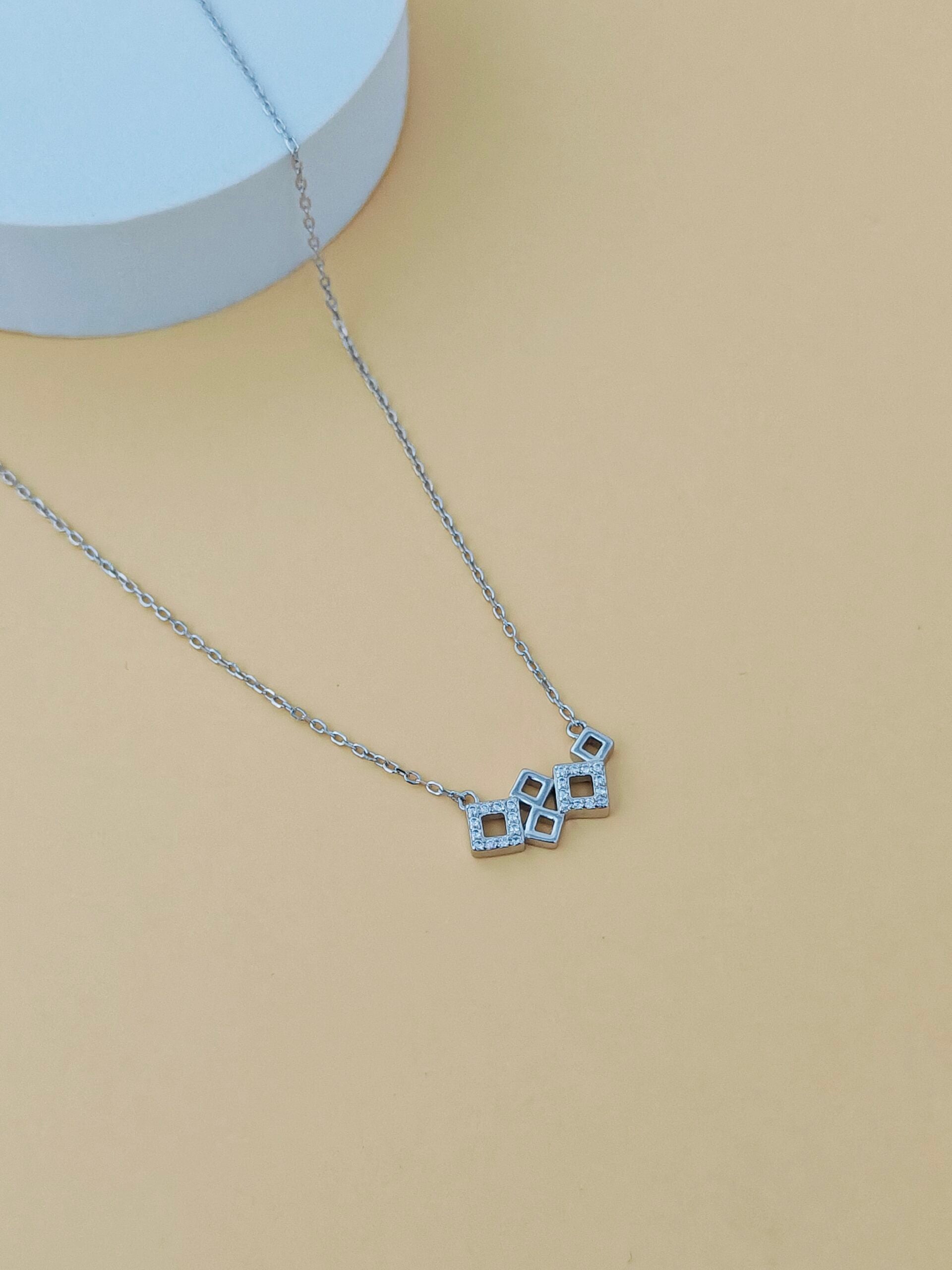 Necklace with a geometric pendant on a beige background