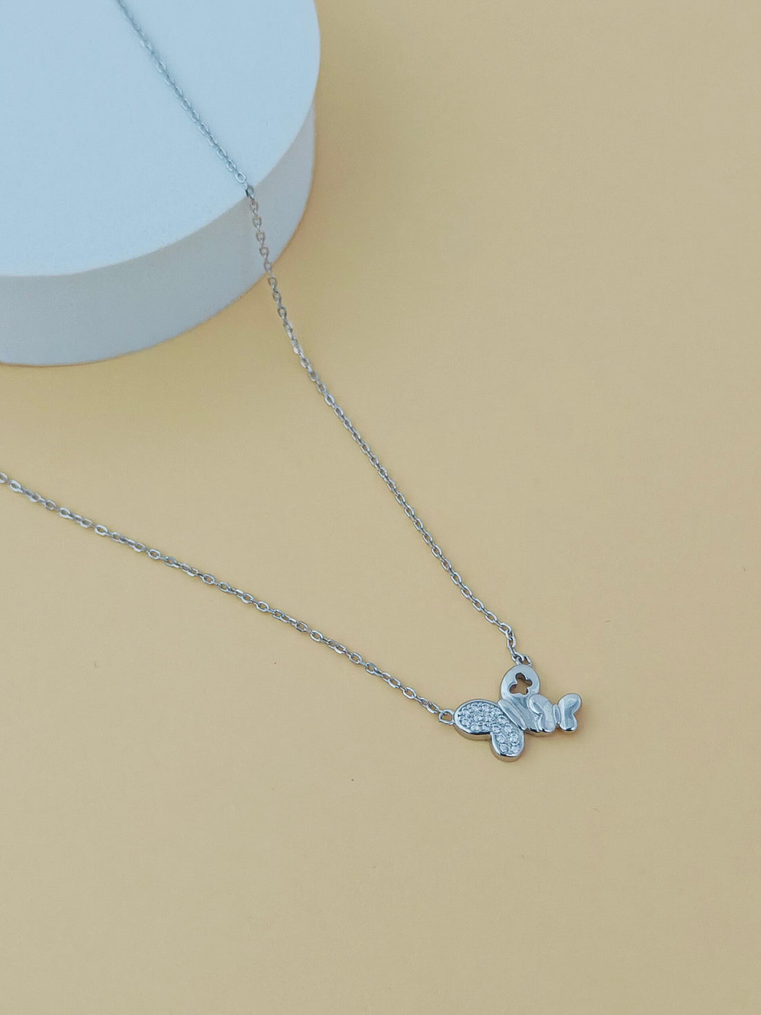 Silver necklace with a small pendant on a beige background