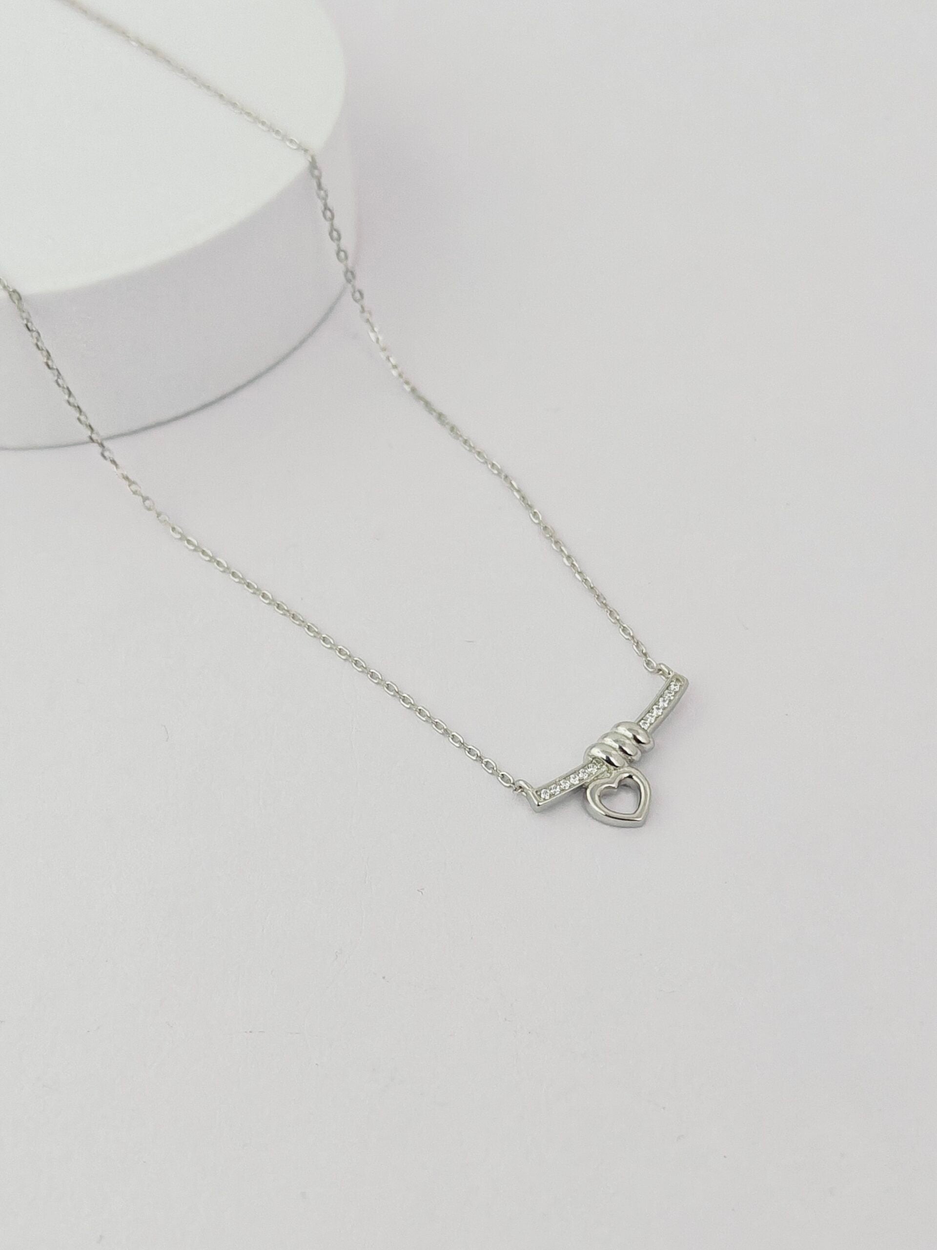 Silver necklace with a heart clasp on a light gray background