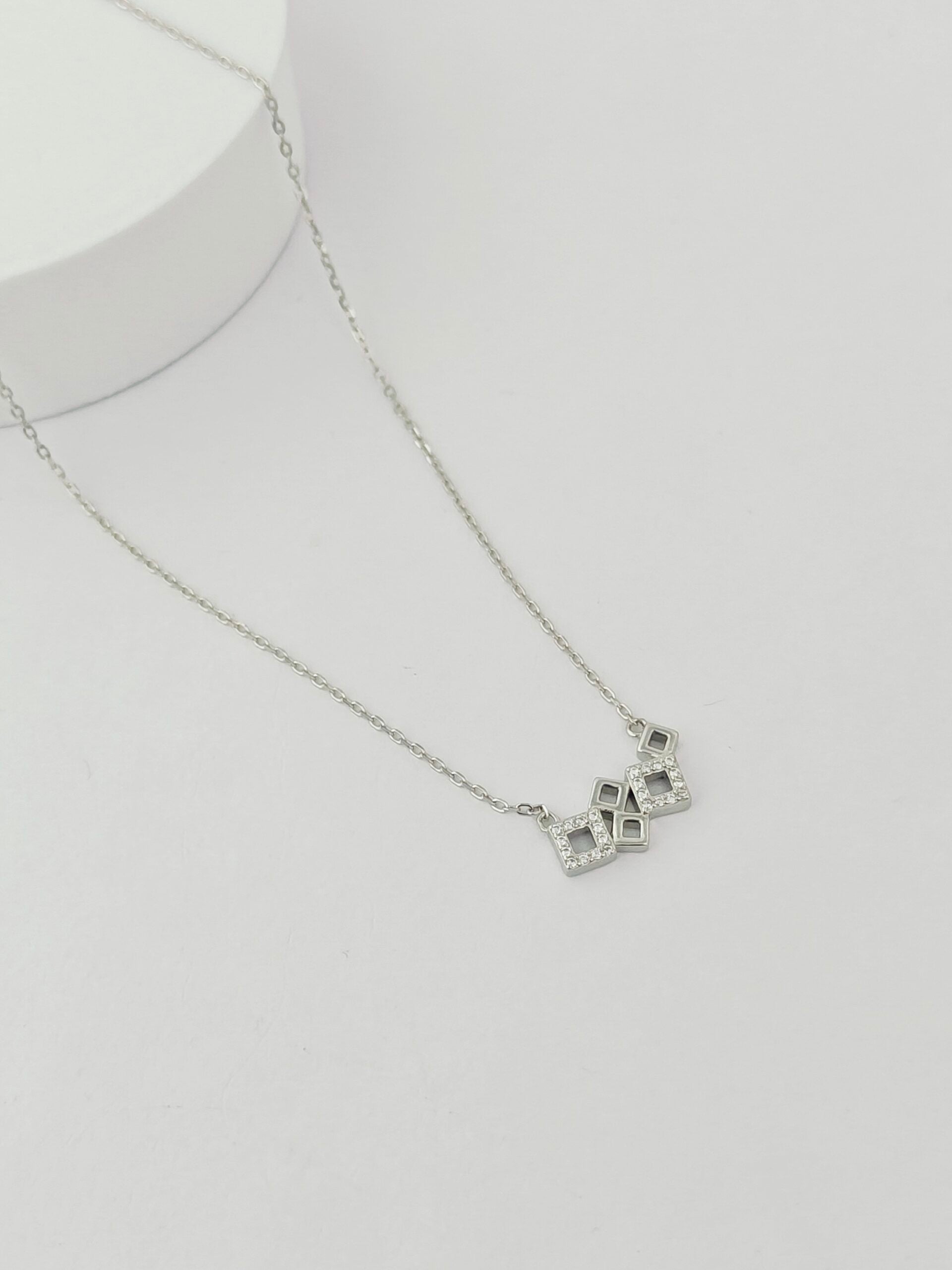 Silver necklace with a geometric pendant on a white background
