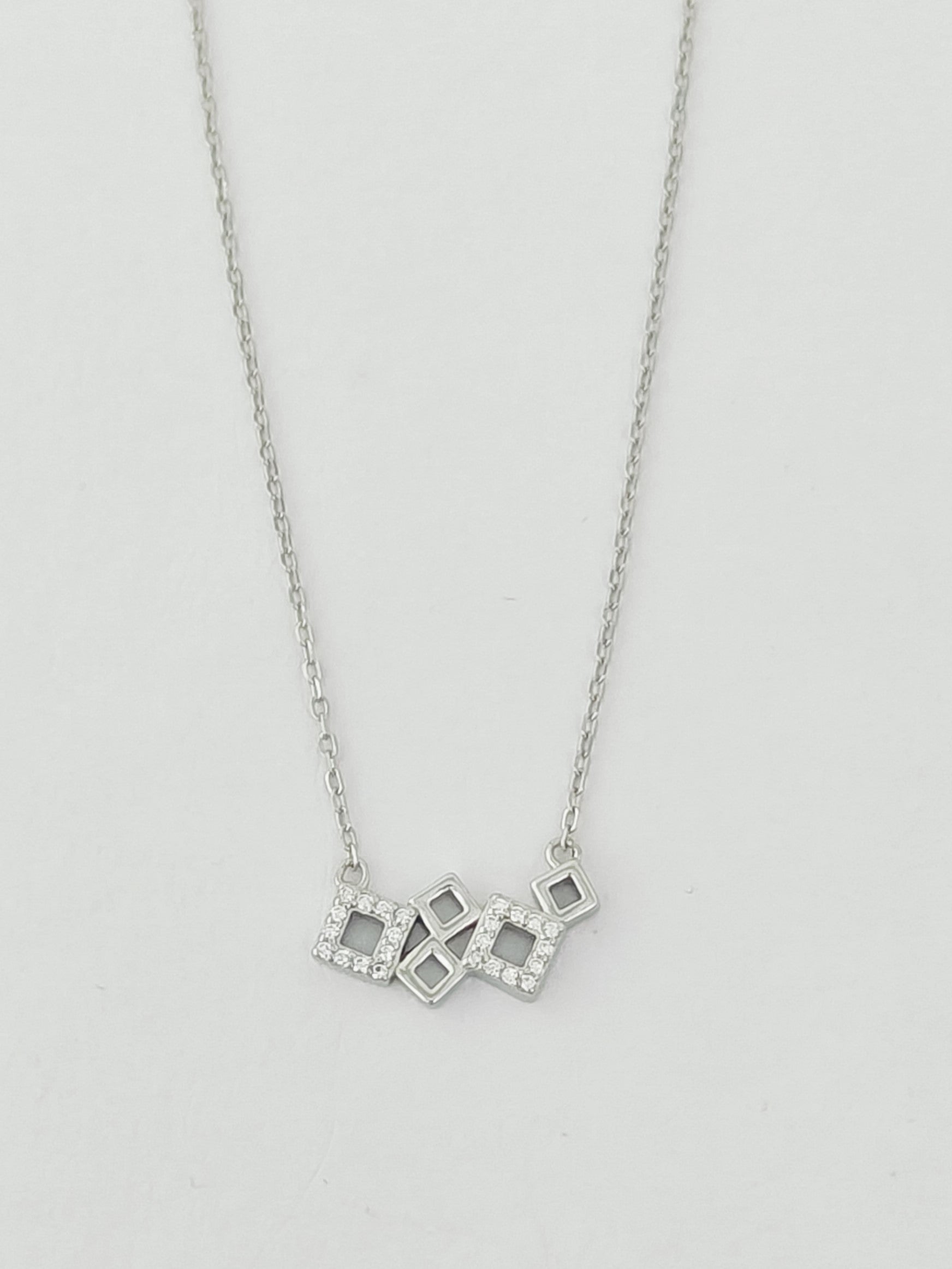 Silver necklace with a geometric pendant on a light gray background