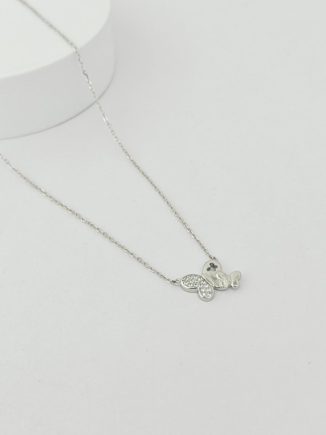 Silver necklace with a heart-shaped pendant on a light gray background