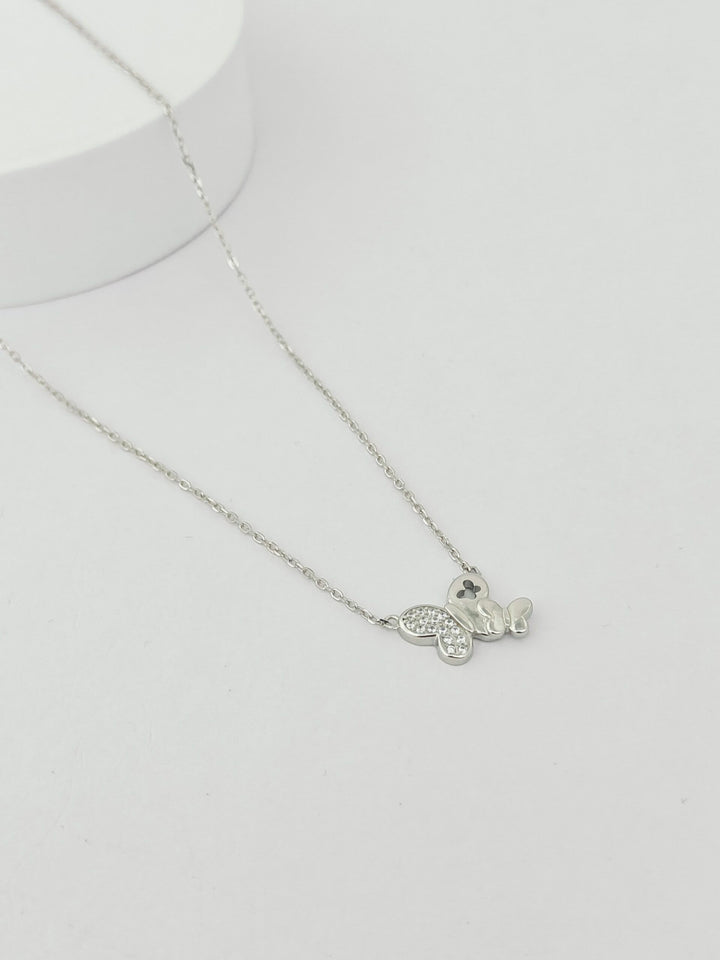 Silver necklace with a heart-shaped pendant on a light gray background