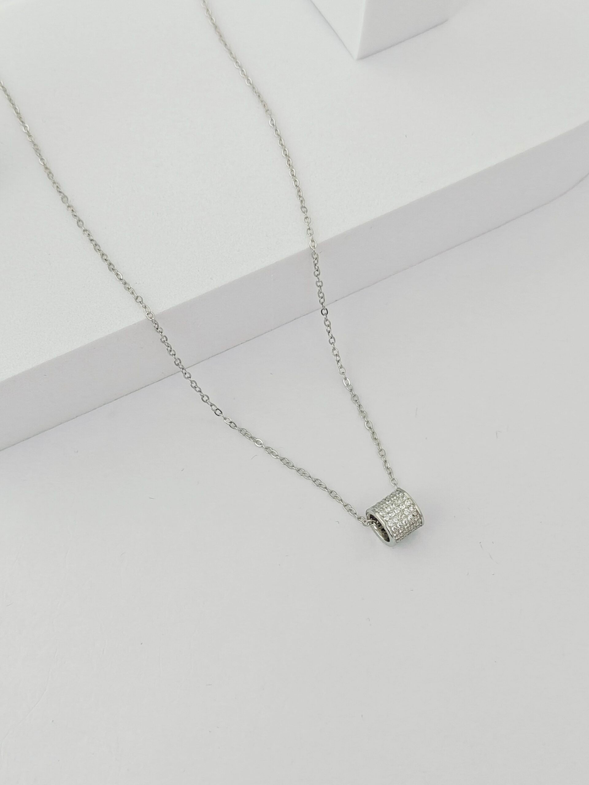 Silver necklace with a small pendant on a light gray background