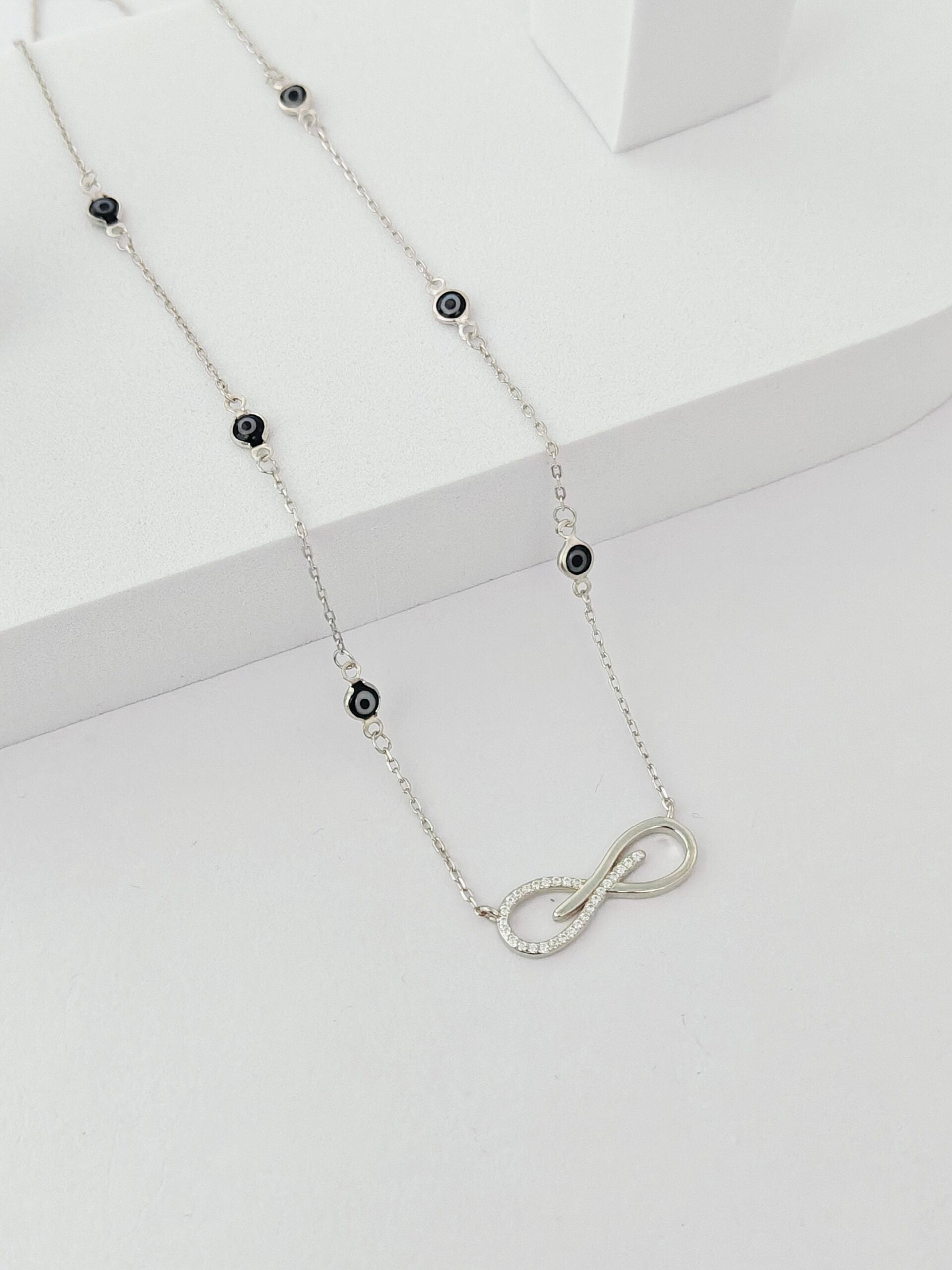 Silver necklace with black beads on a white background