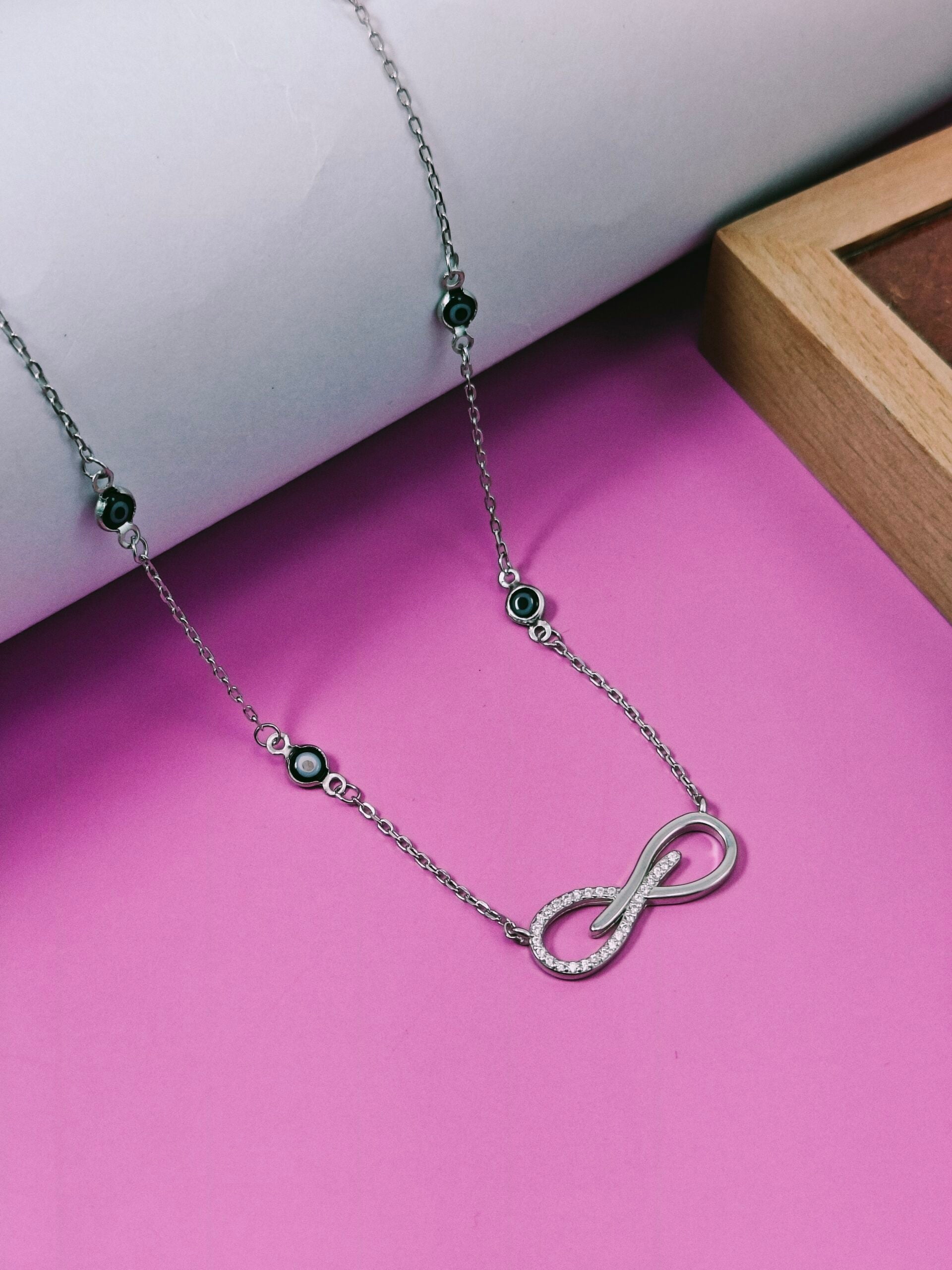 Necklace with an infinity symbol pendant on a pink surface