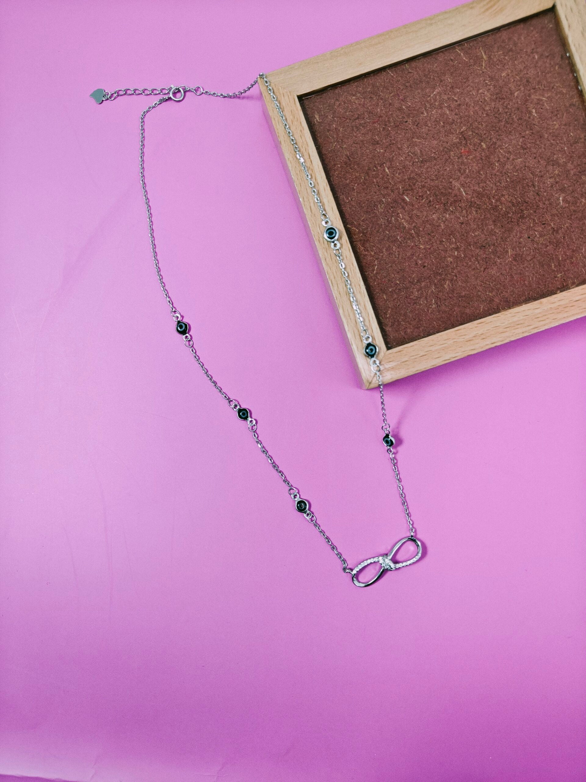 Necklace with an infinity symbol pendant on a pink background