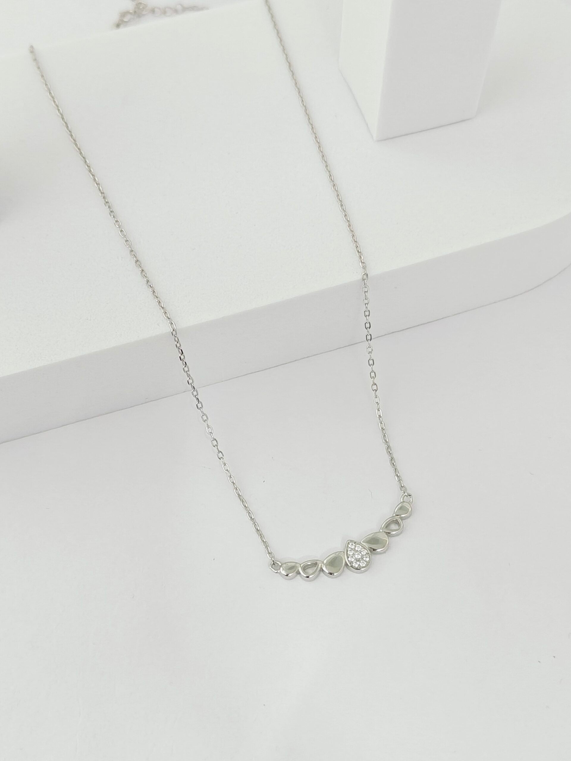 Silver necklace with a heart pendant on a white background