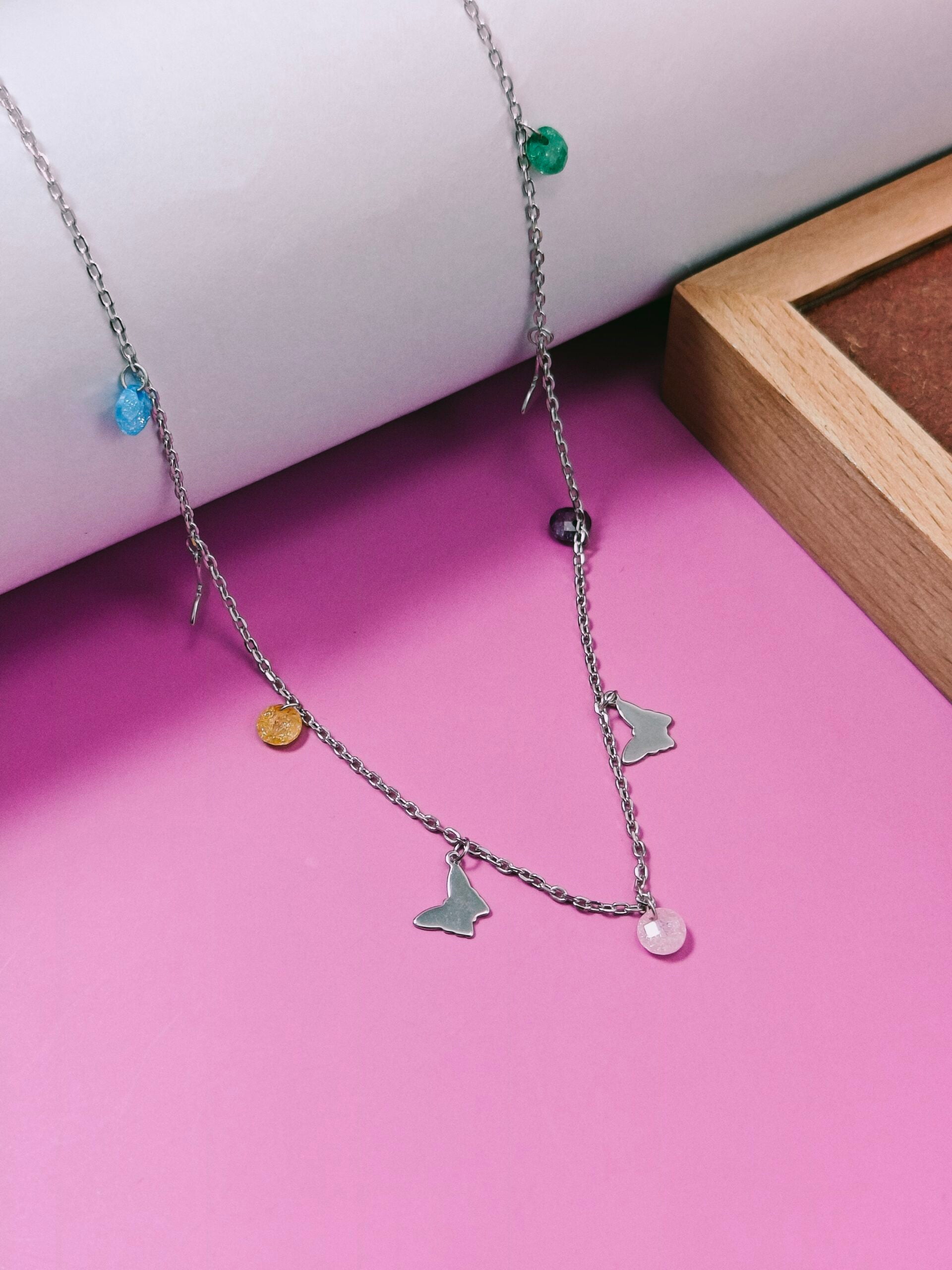 Necklace with various charms on a pink surface