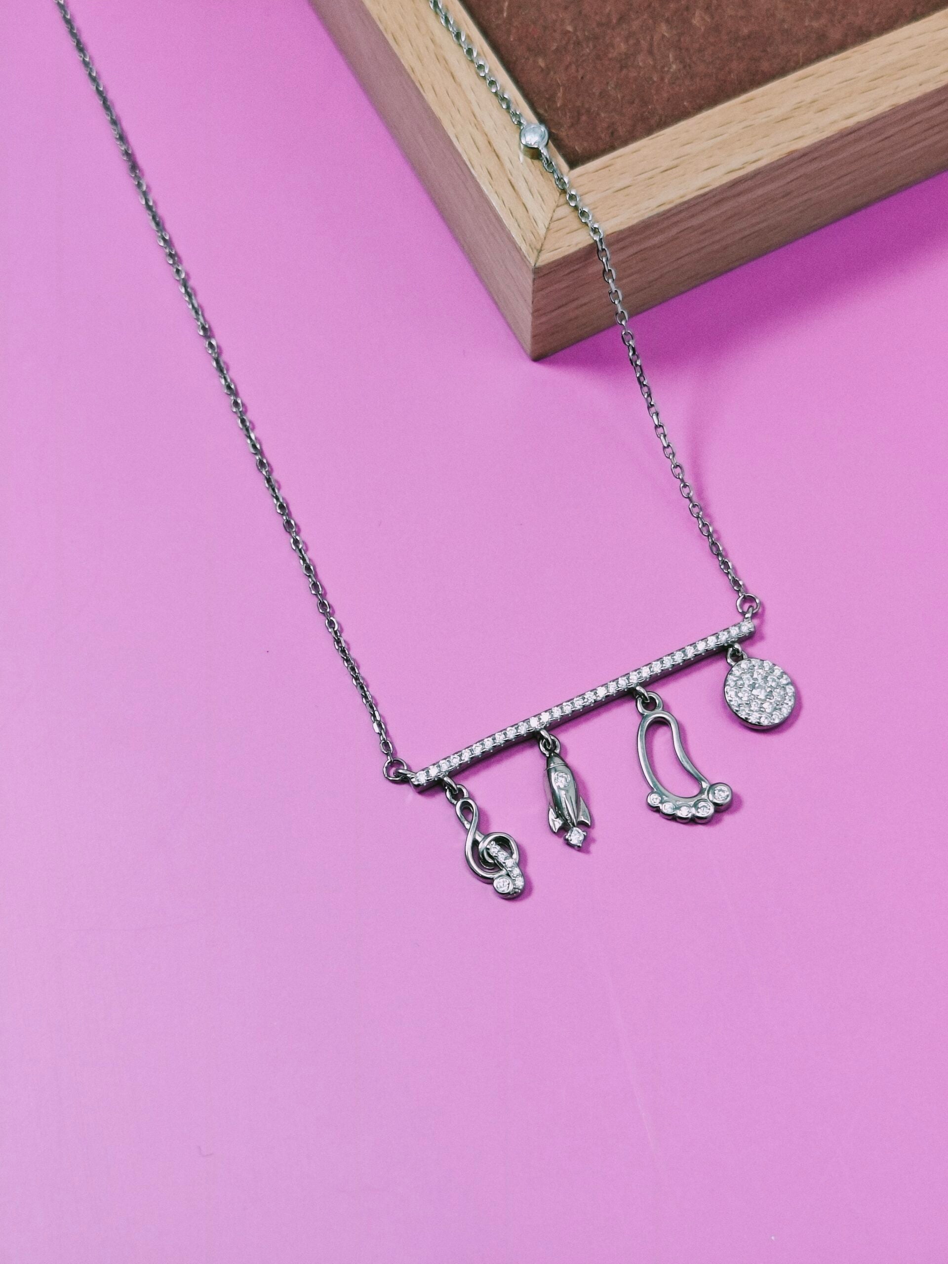 Necklace with various charms on a pink background