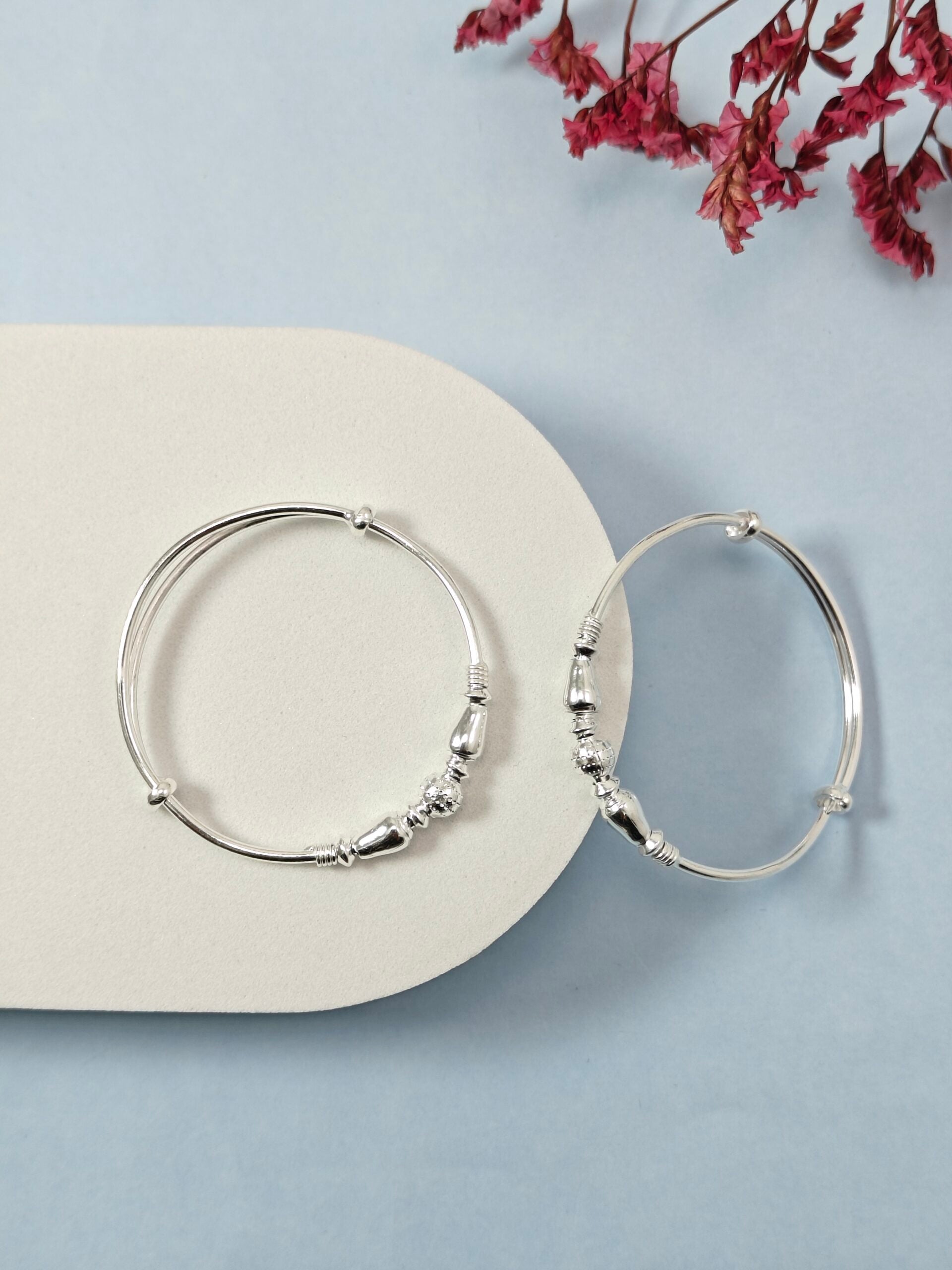 Silver hoop earrings on a light blue surface with dried pink flowers.