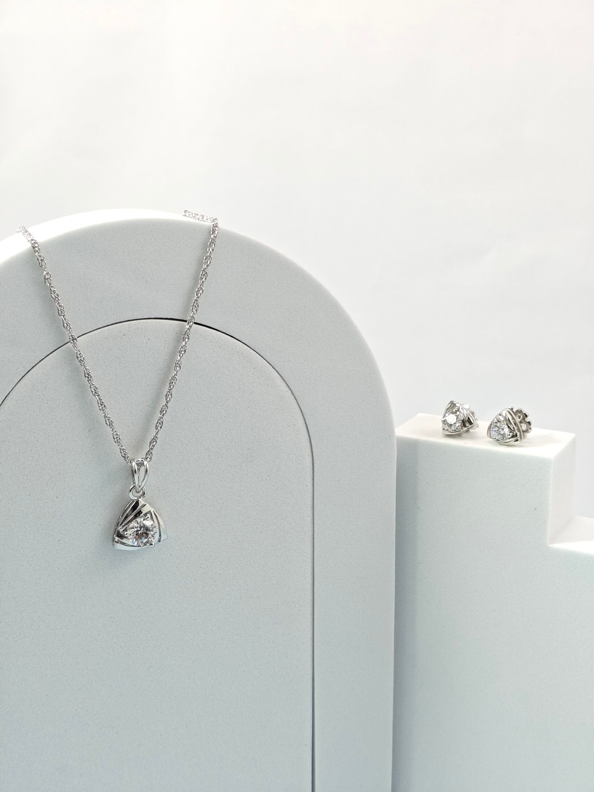 Silver necklace and earrings on a white surface