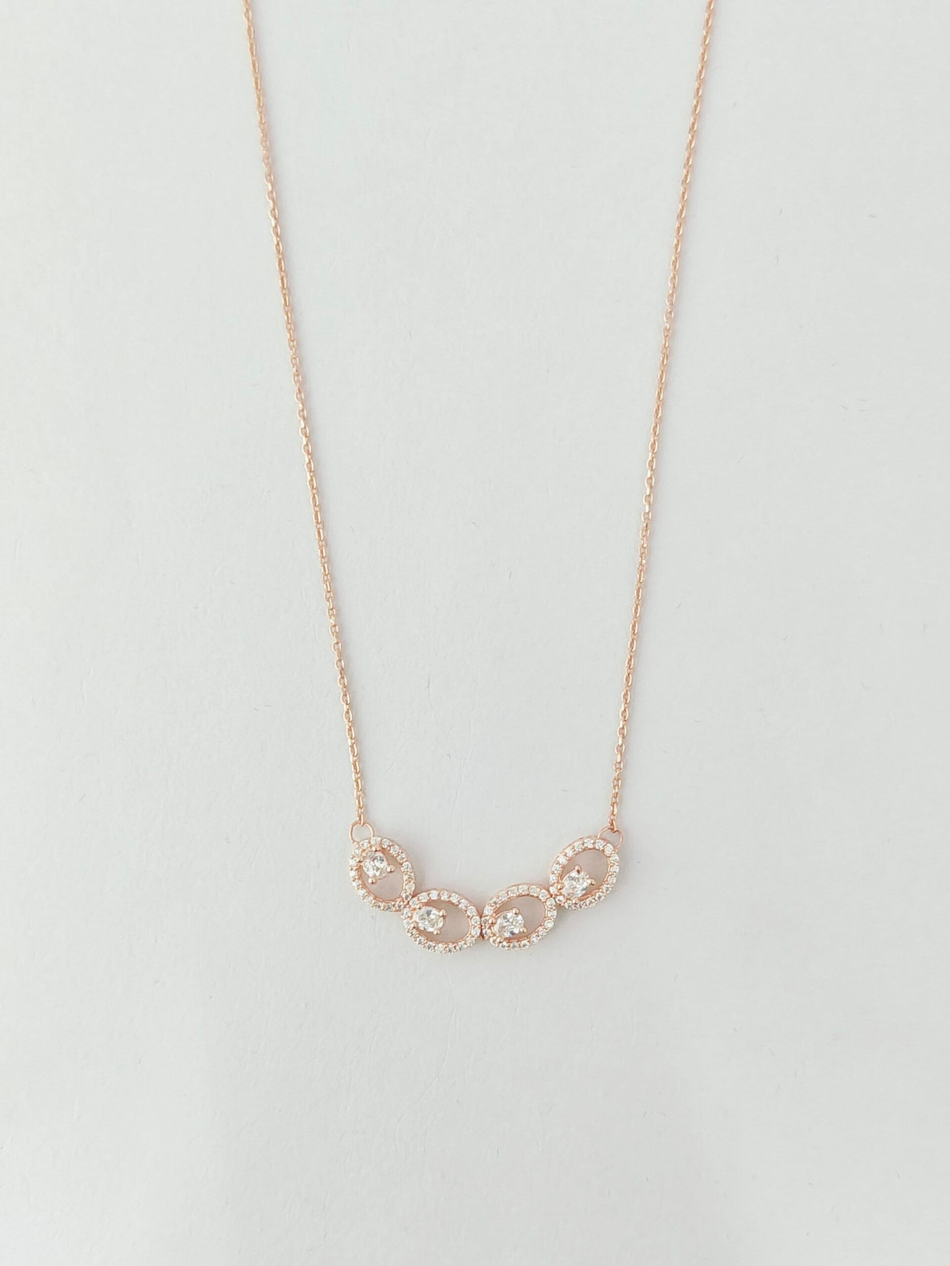 Delicate gold necklace with small circular pendants on a light gray background