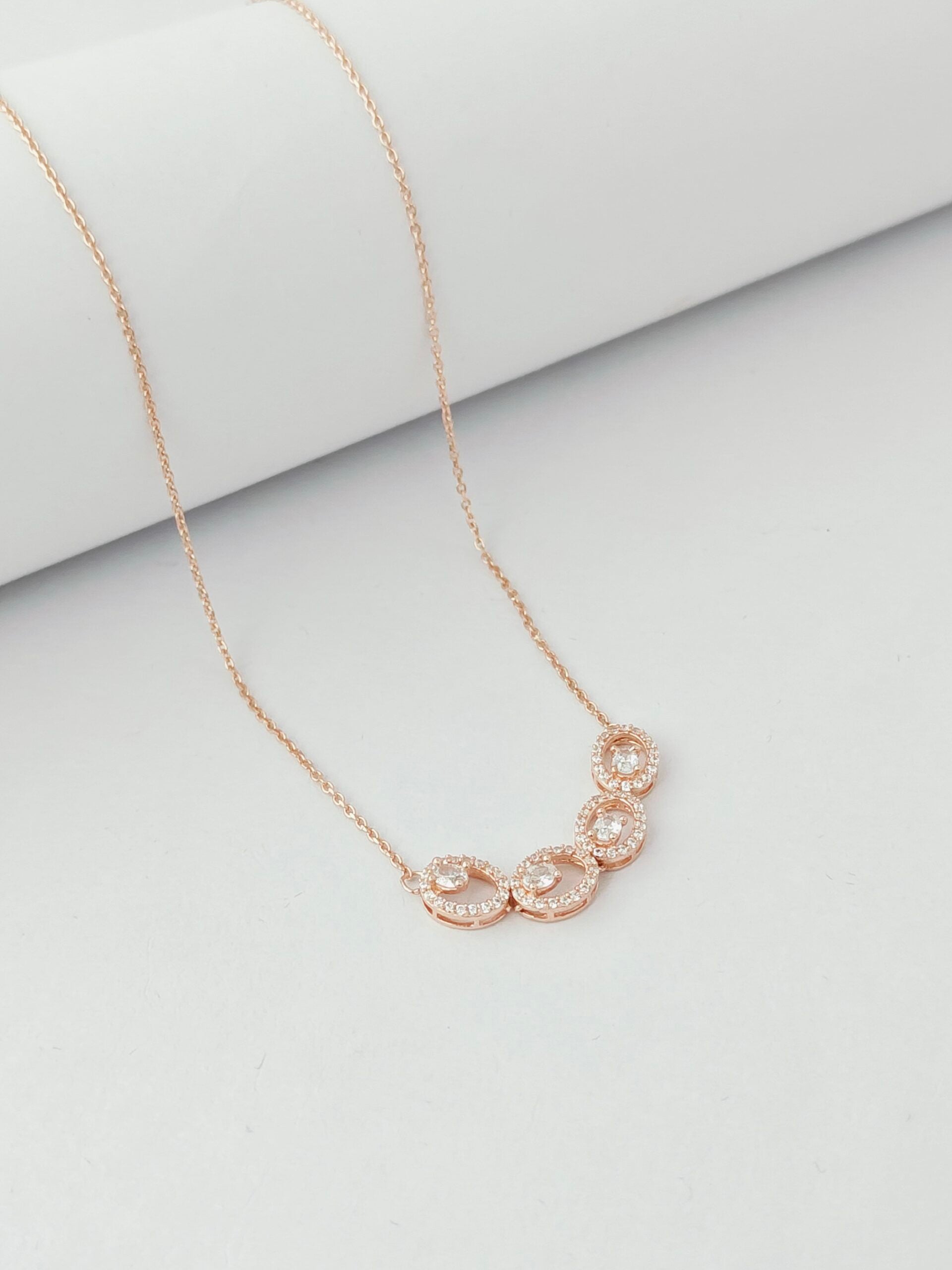 Rose gold necklace with a floral pendant on a light gray background