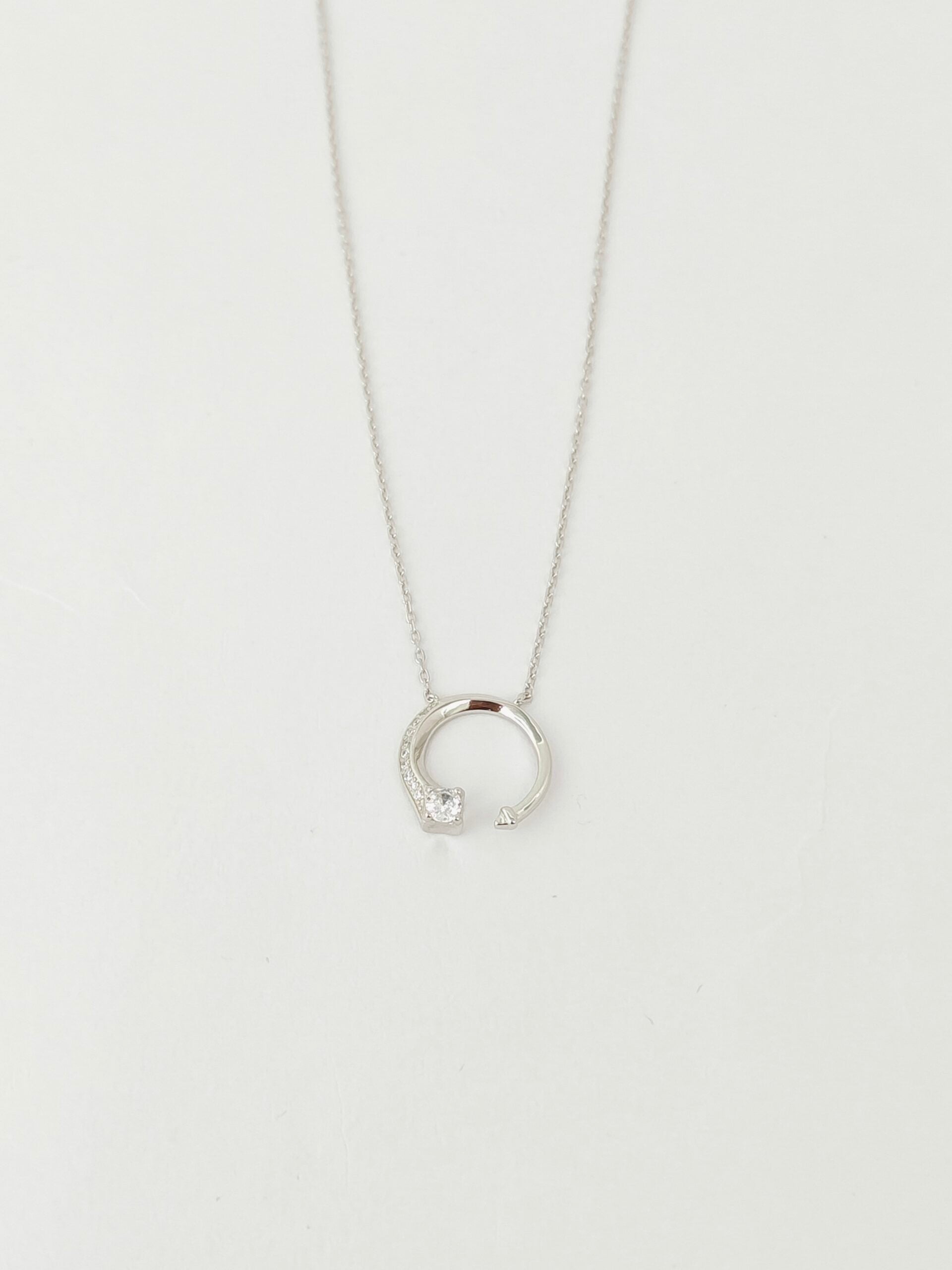 Silver necklace with a small pendant on a light gray background