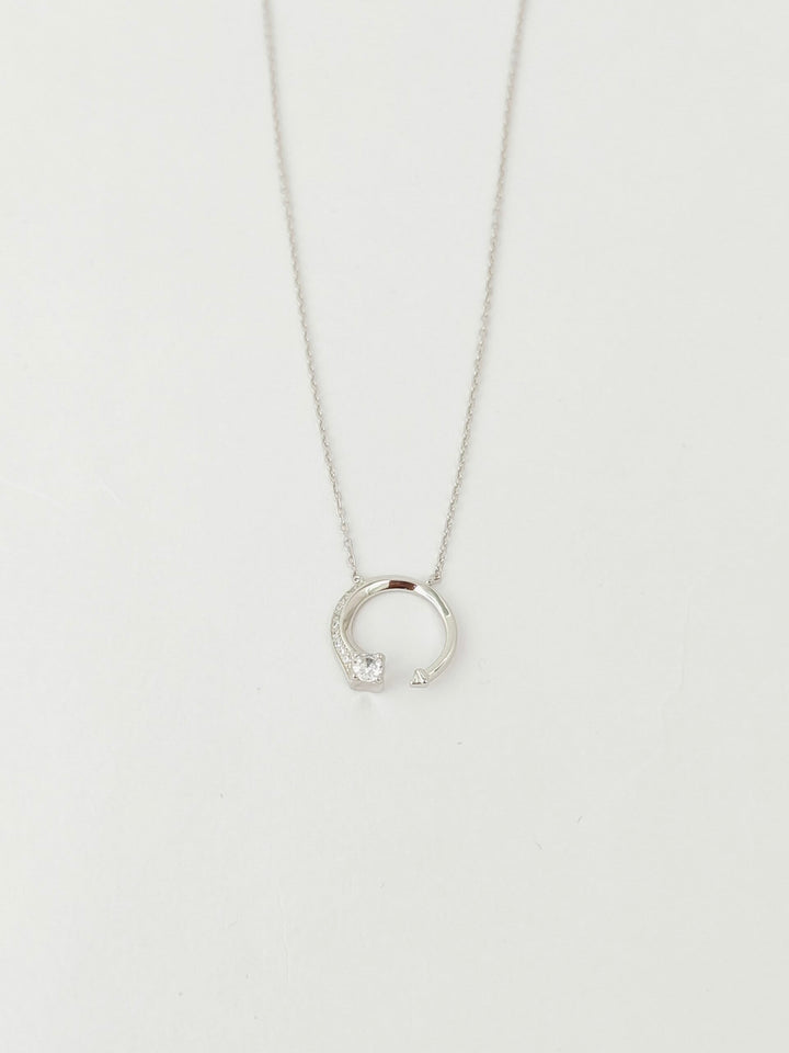 Silver necklace with a small pendant on a light gray background