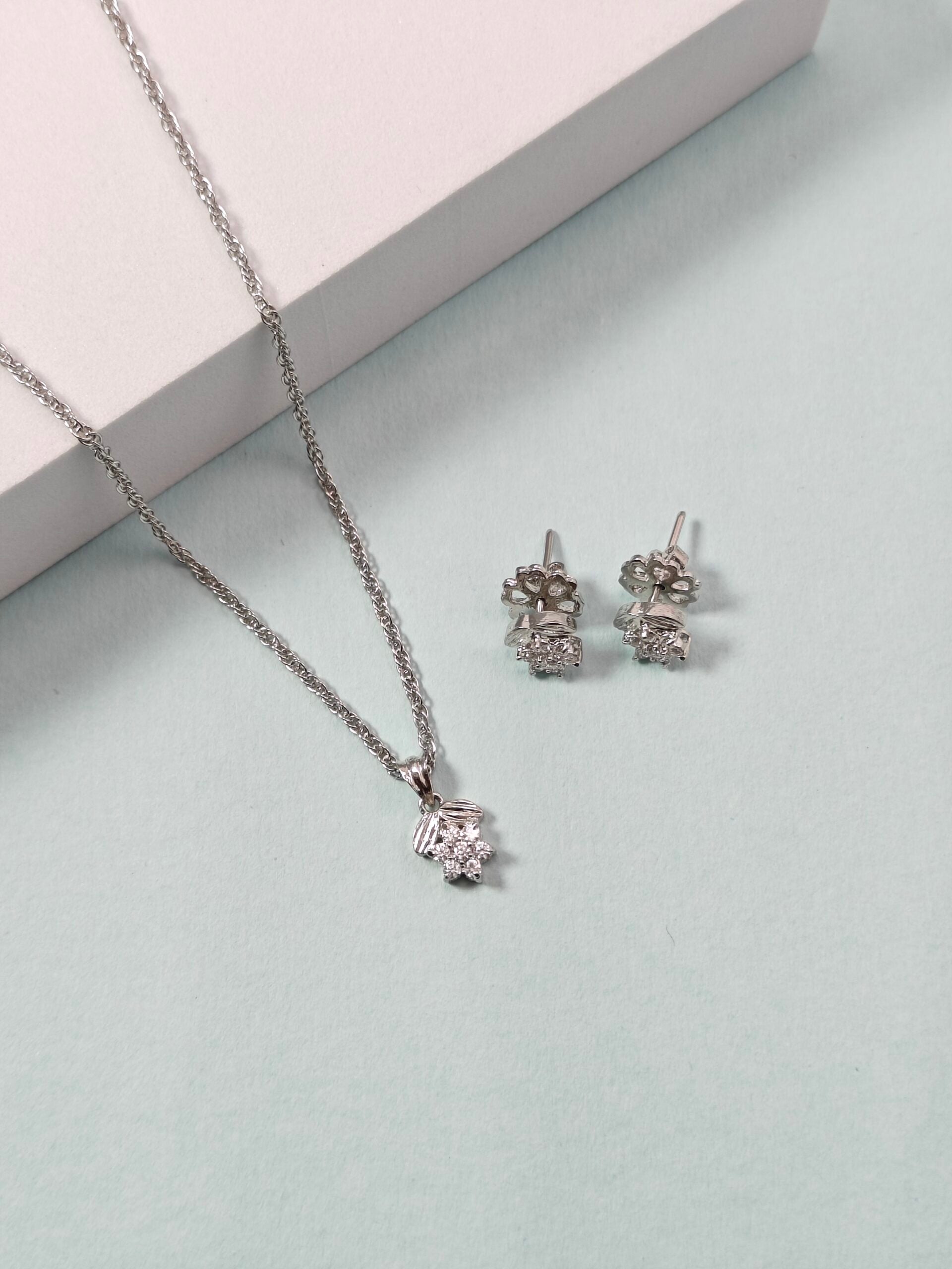 Silver necklace and earrings on a light gray surface