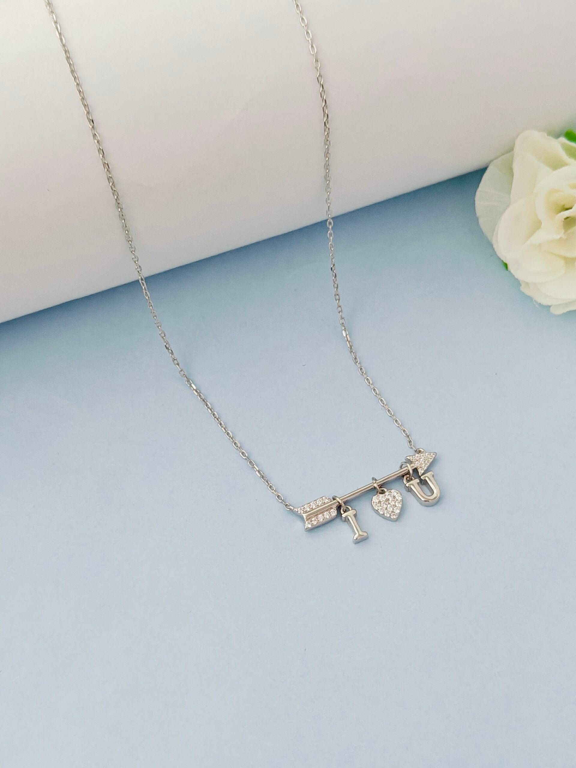 Silver necklace with 'I love you' pendant on a light blue background