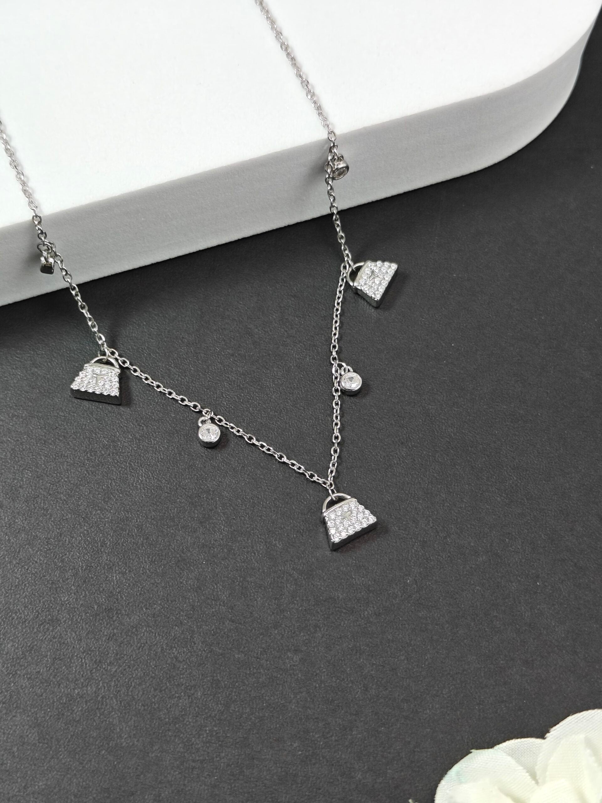 Silver necklace with small pendant charms on a dark surface