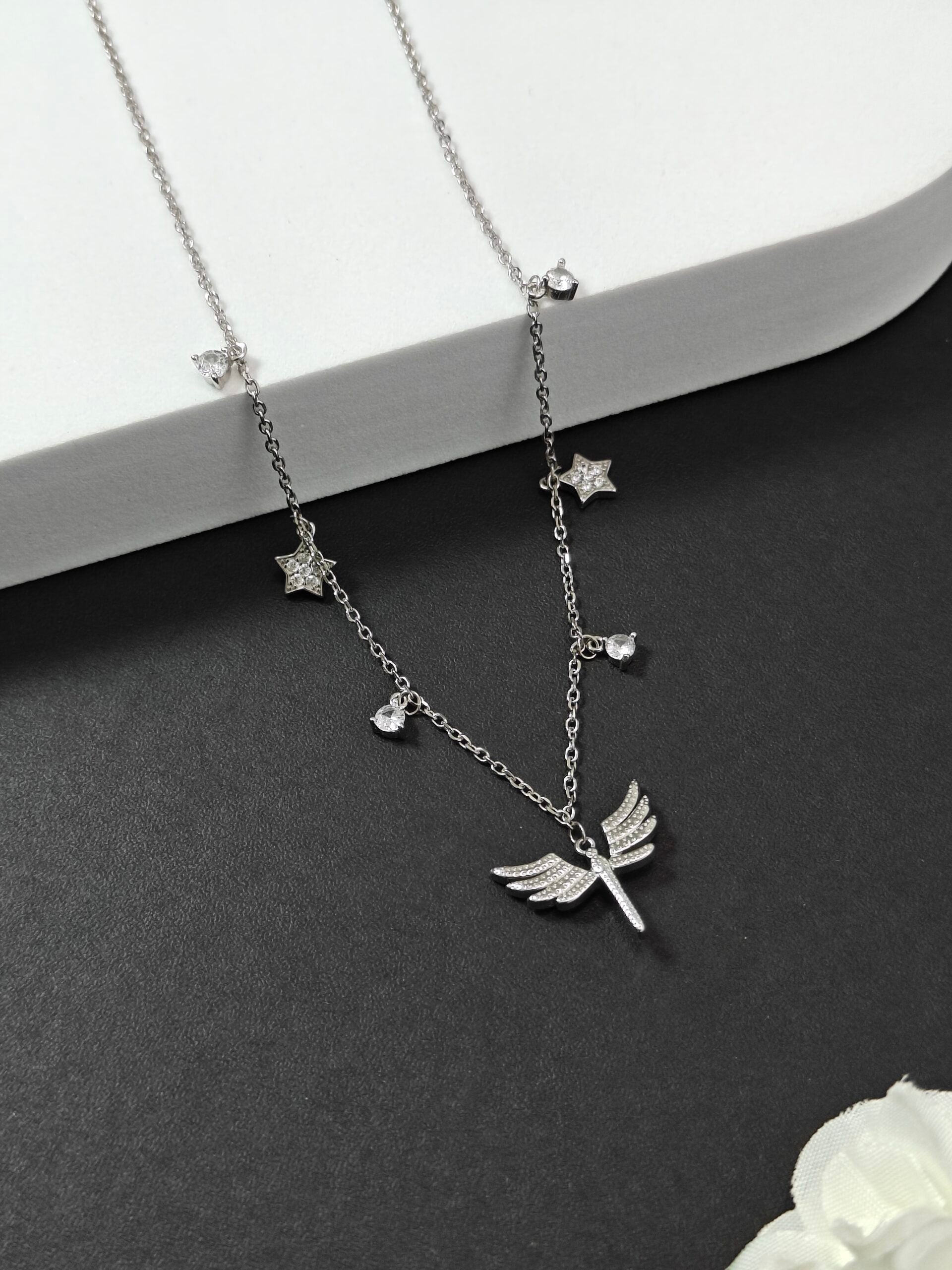 Silver necklace with dragonfly pendant on a dark surface