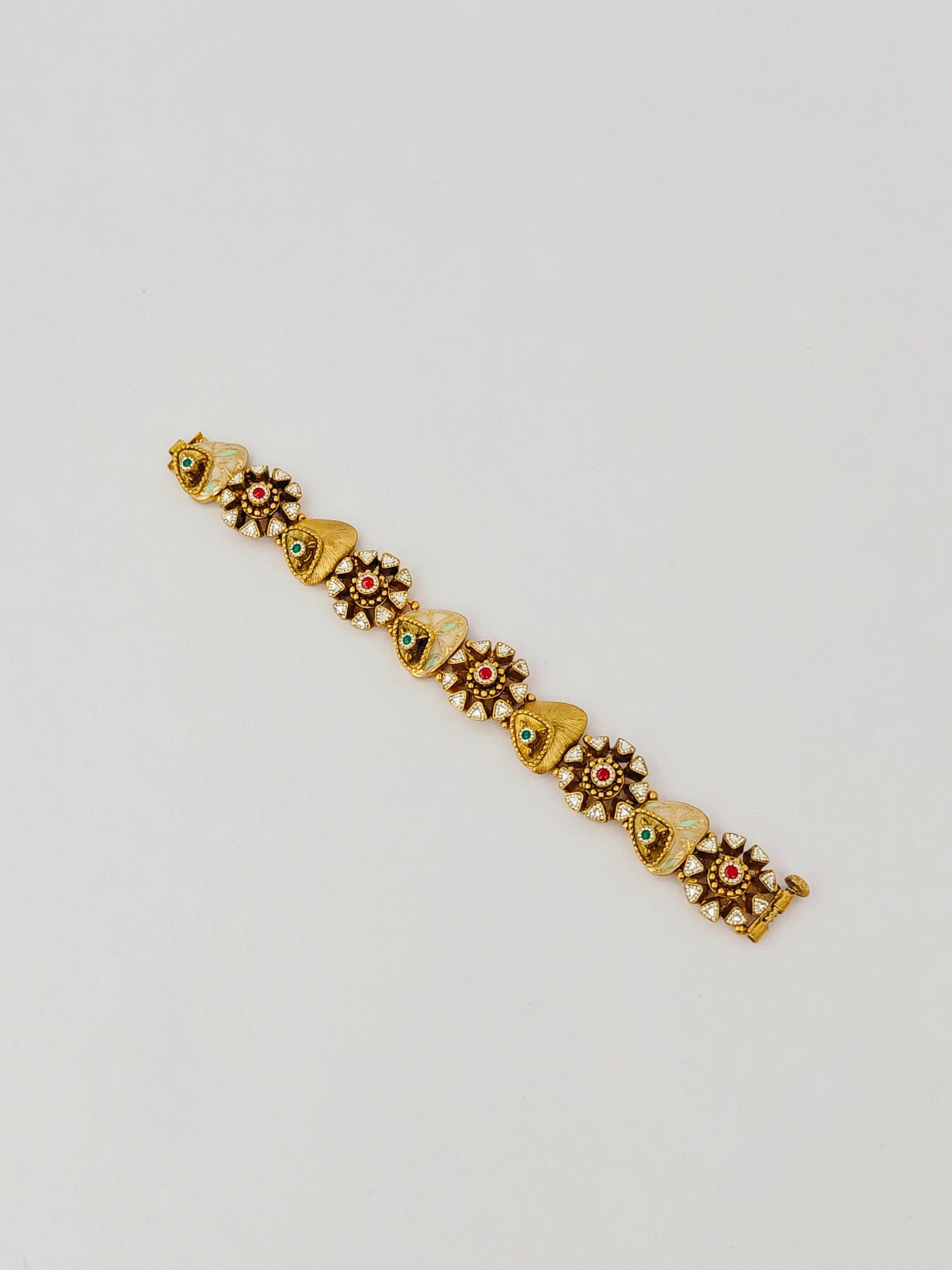 Gold bracelet with floral designs on a light gray background