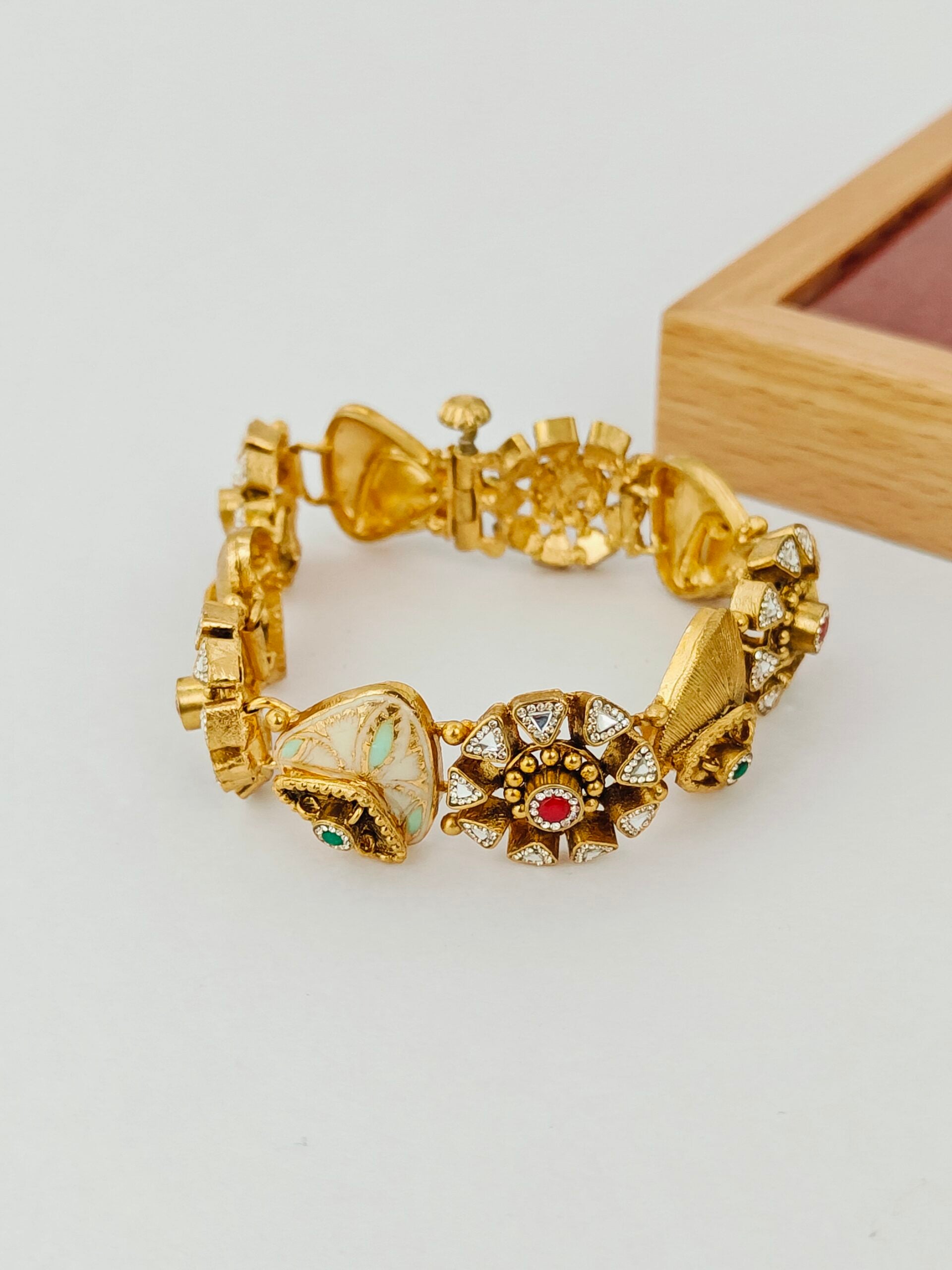 Gold bracelet with decorative elements on a light gray background