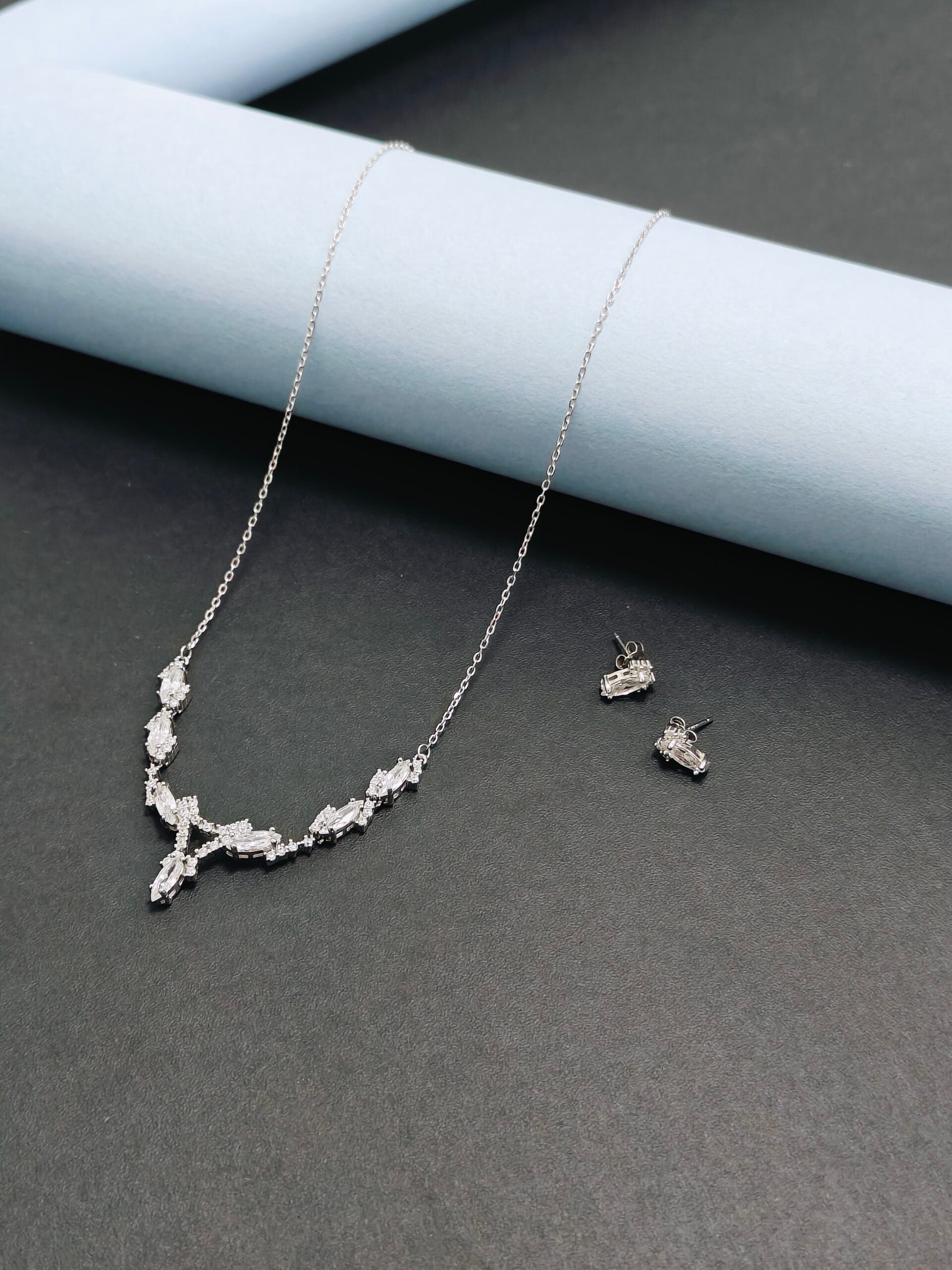 Silver necklace and earrings on a dark surface