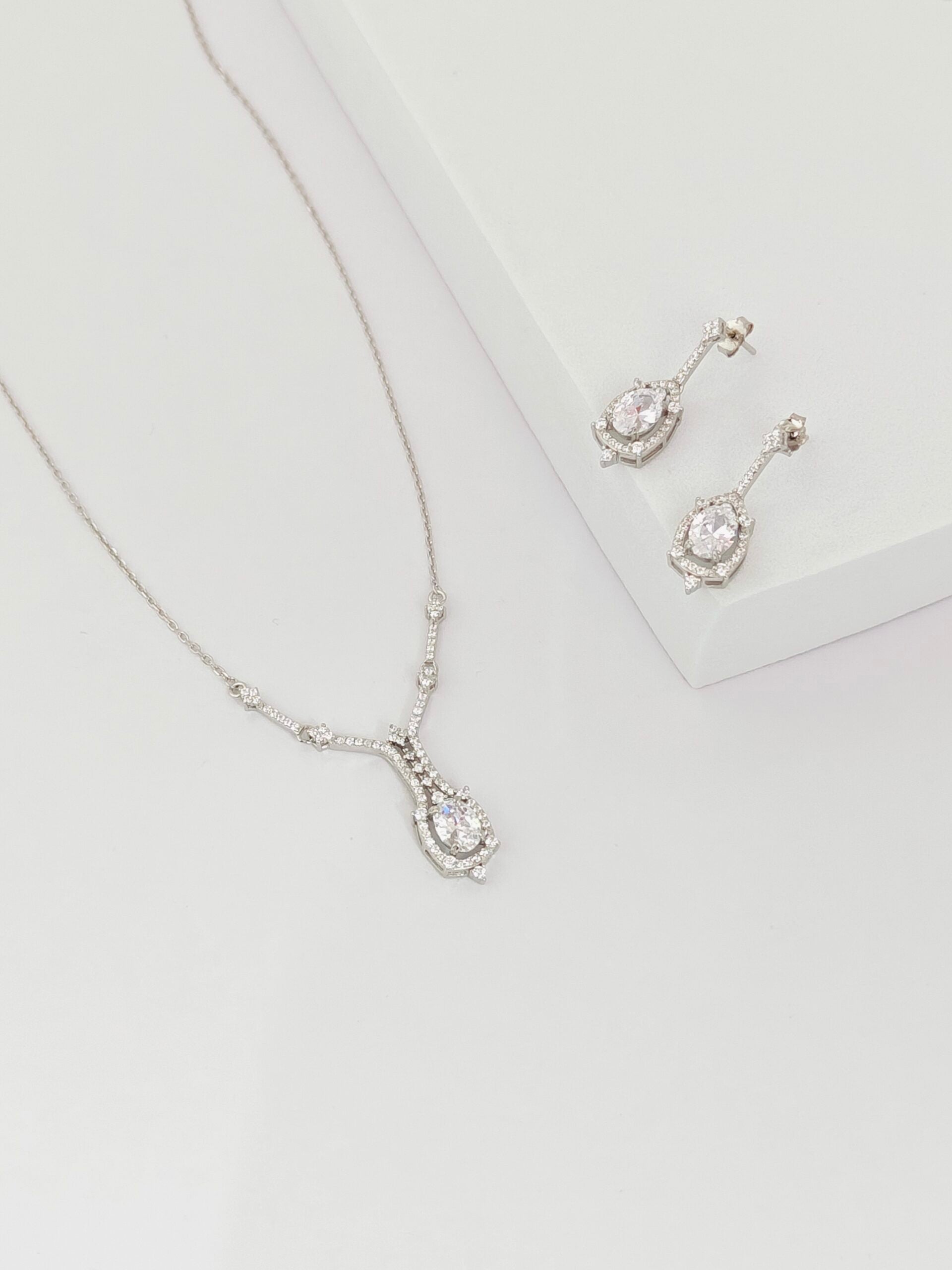 Silver necklace and earrings on a light gray background