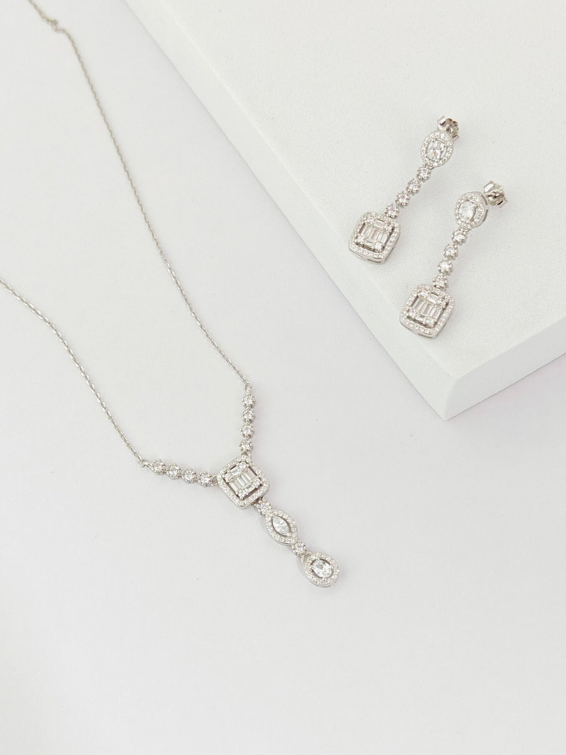 Silver necklace and earrings on a white background