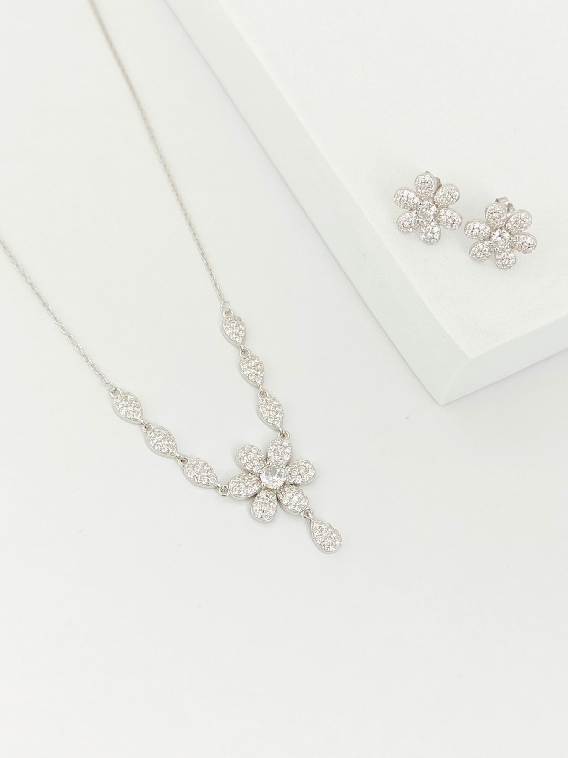 Silver floral necklace and earrings on a white background