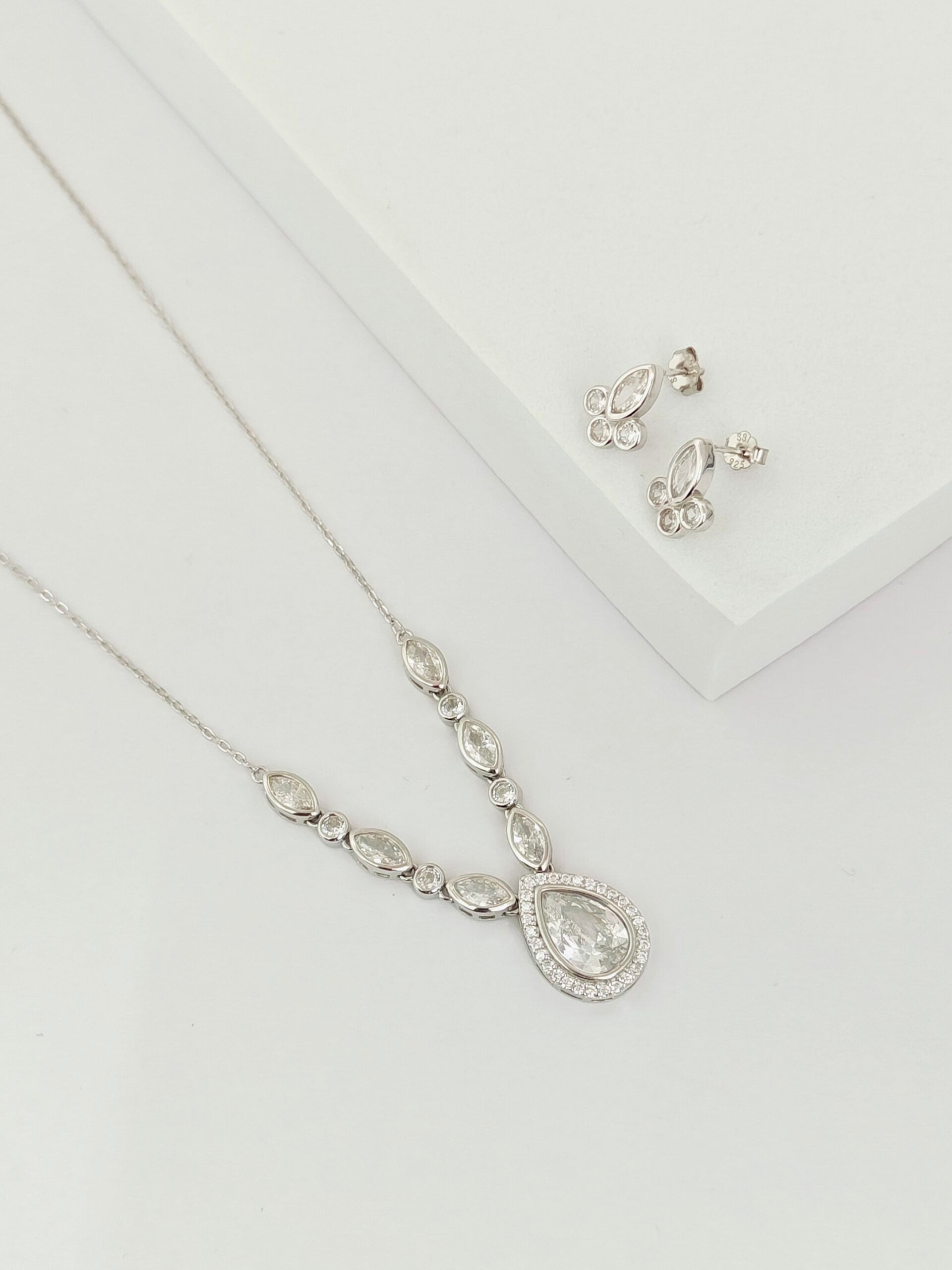 Silver necklace and earrings on a white background