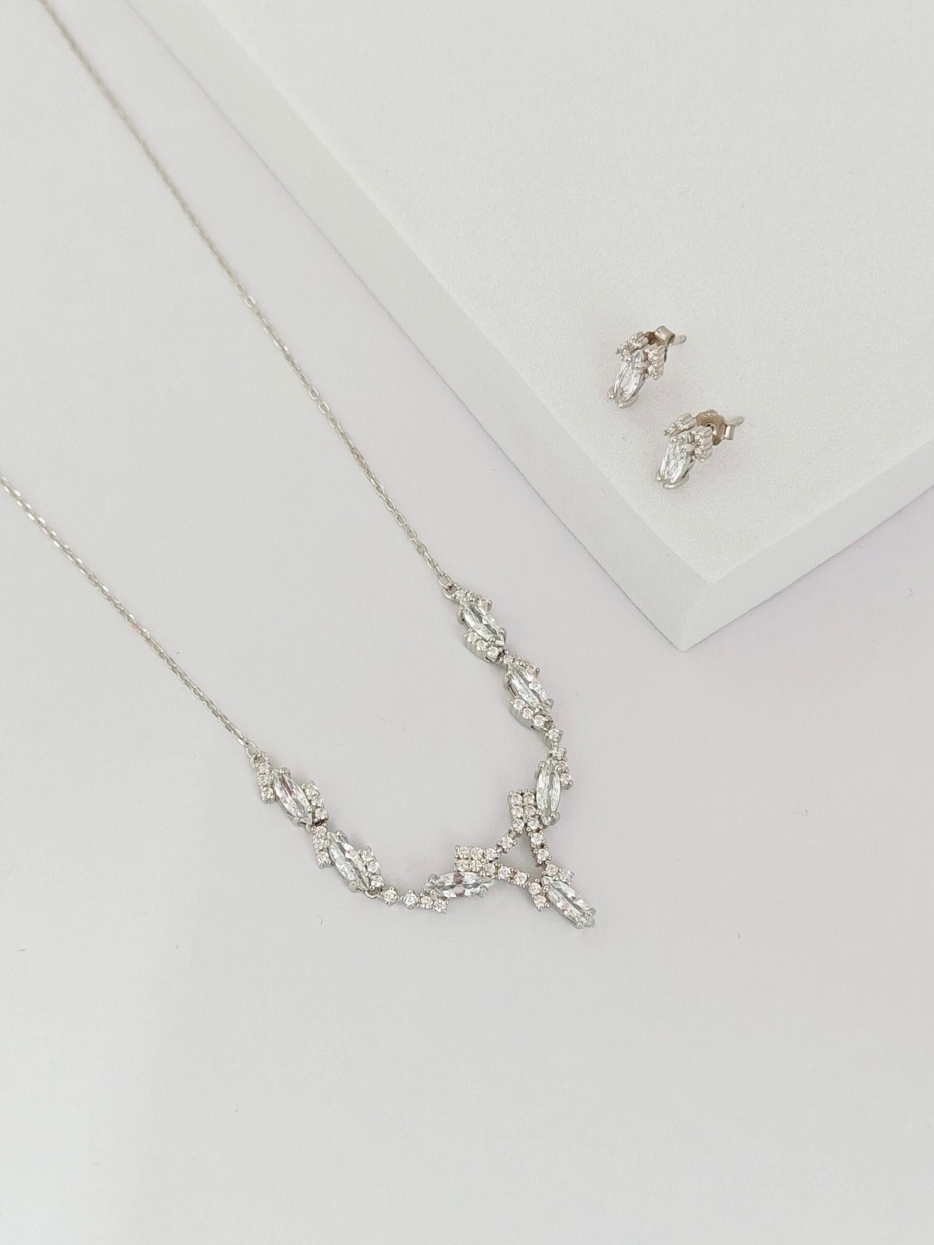 Silver necklace and earrings on a light gray background