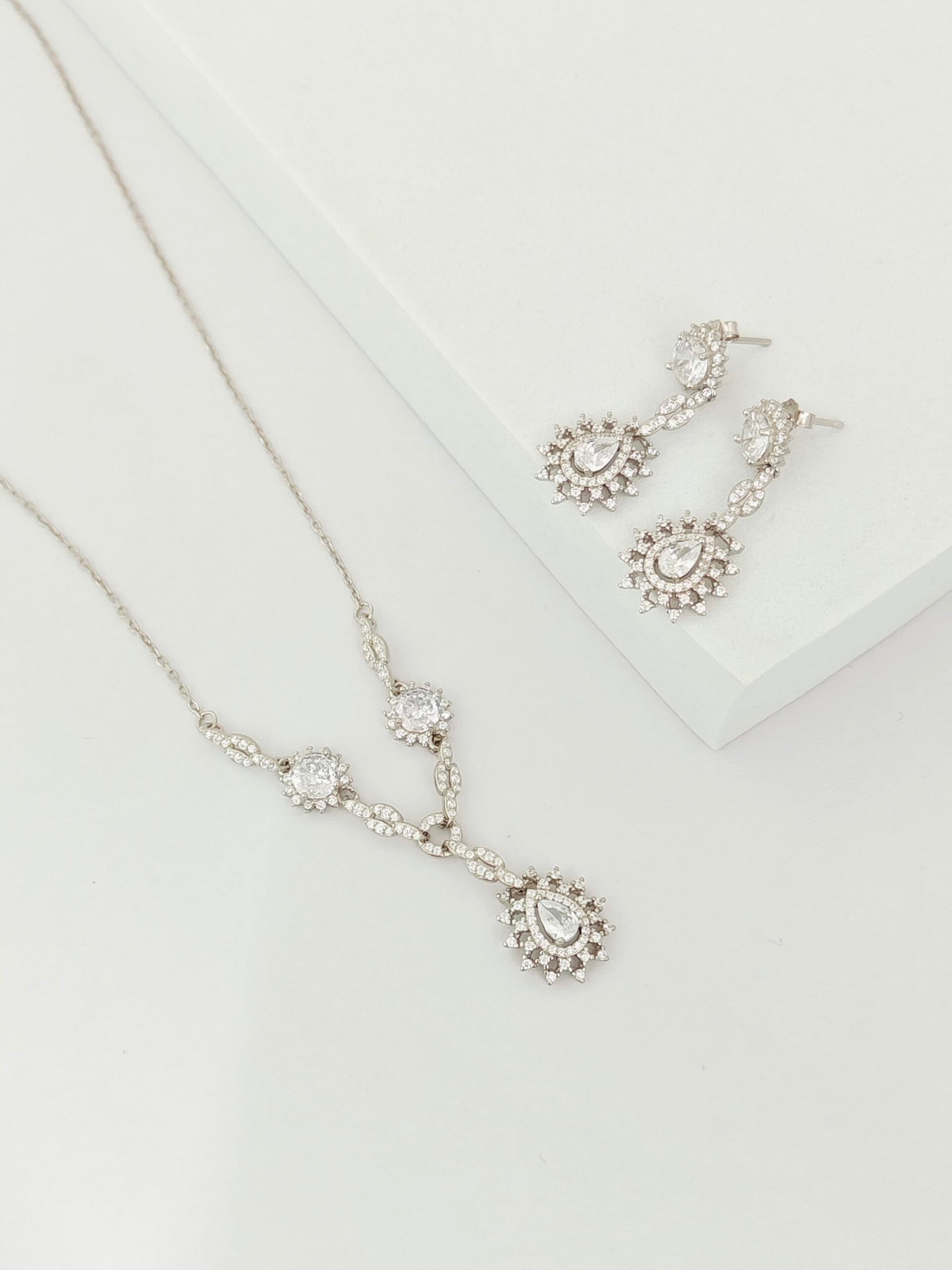 Silver necklace and earrings on a white background