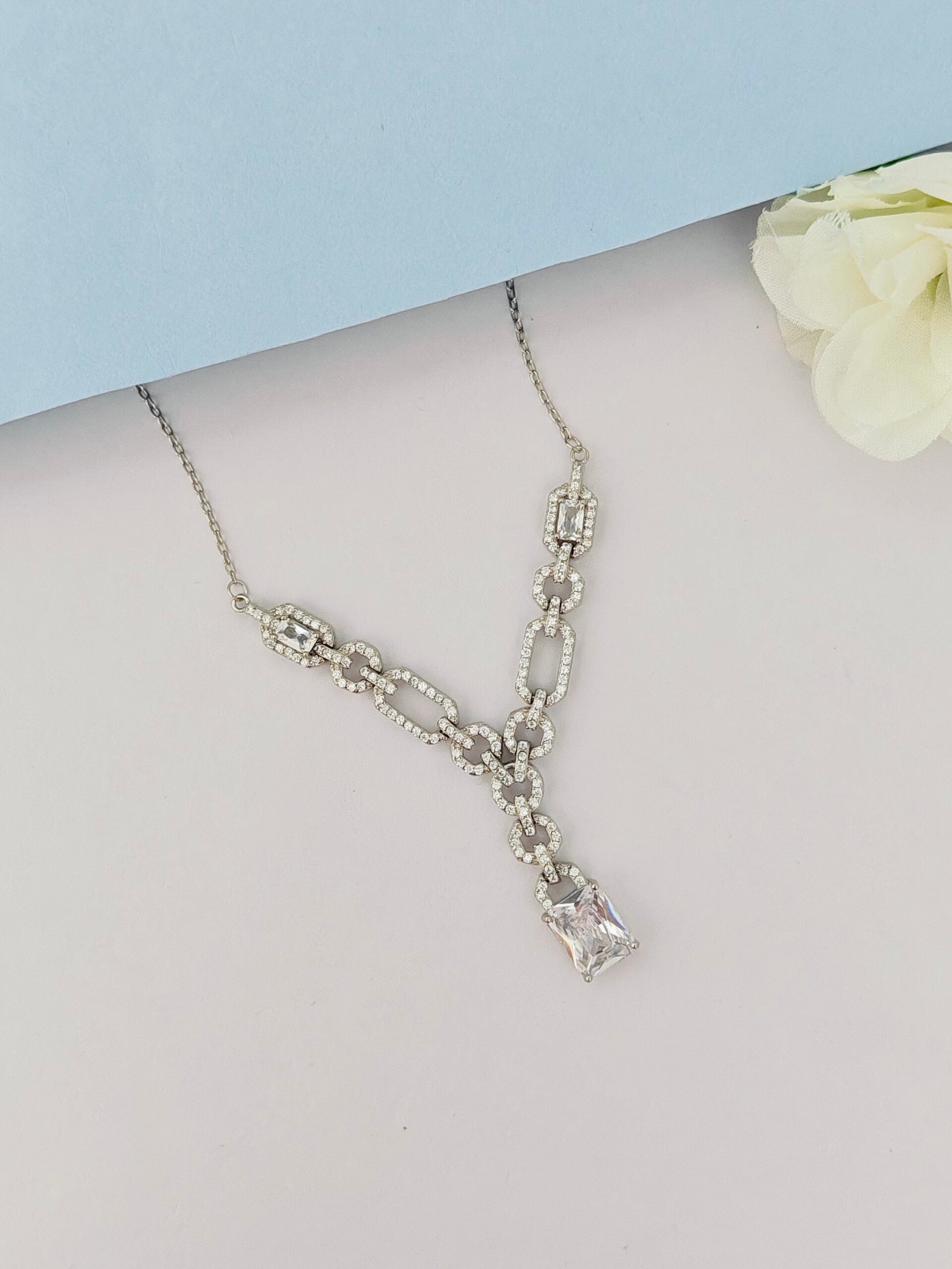 Silver necklace on a mannequin with a light blue background