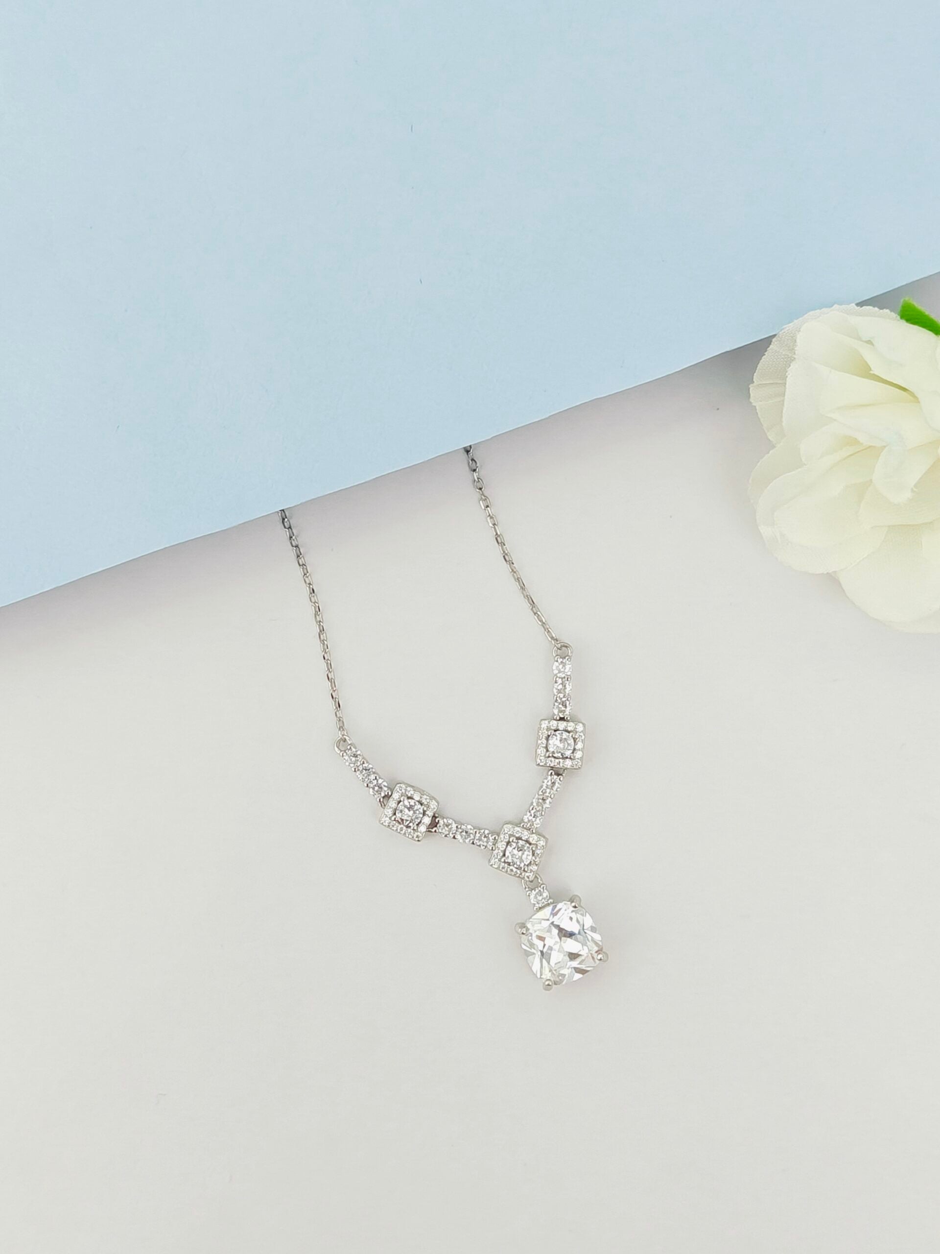 Silver necklace with a pendant on a mannequin bust against a light blue background