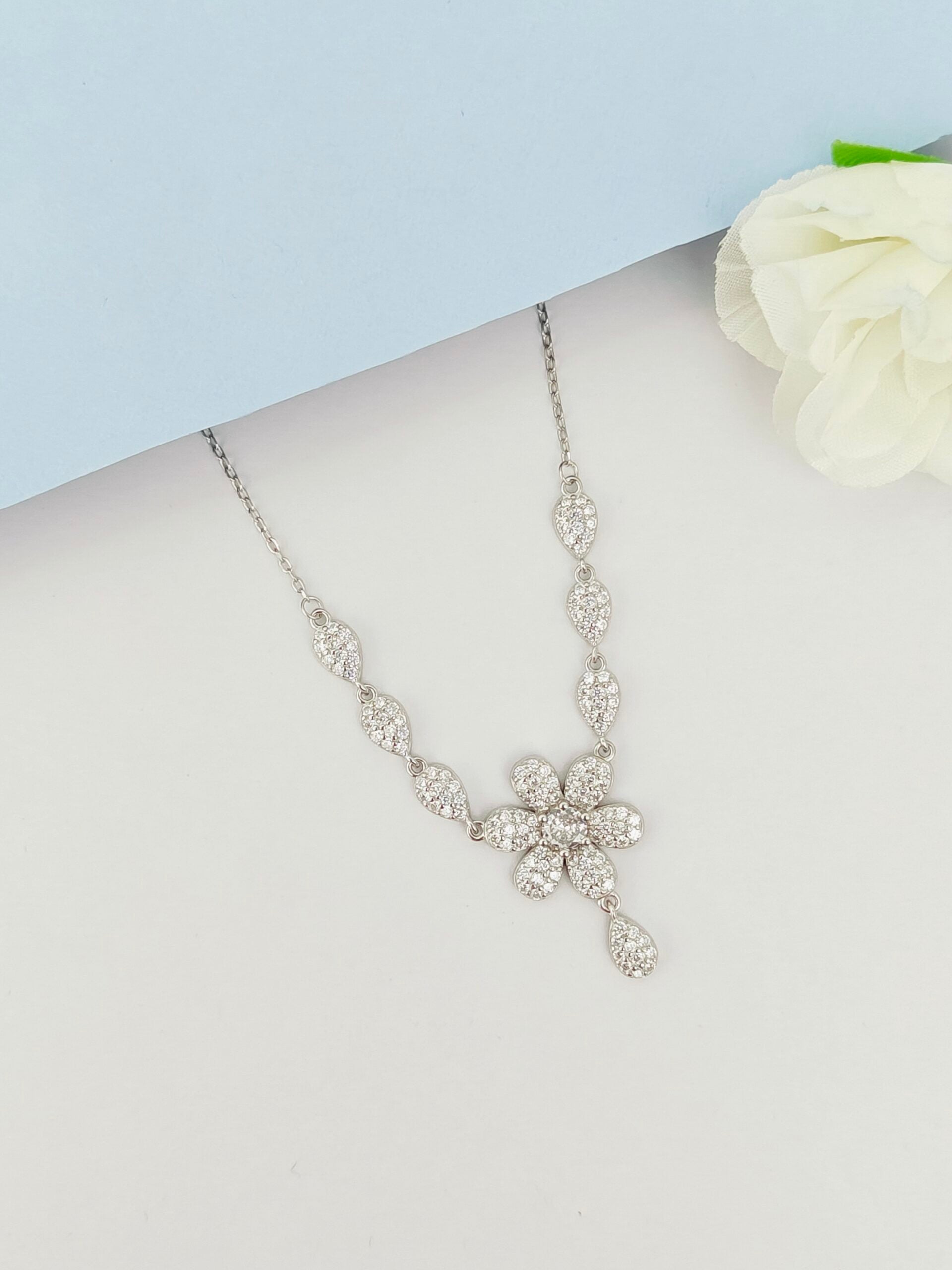 Silver necklace on a mannequin with a light blue background