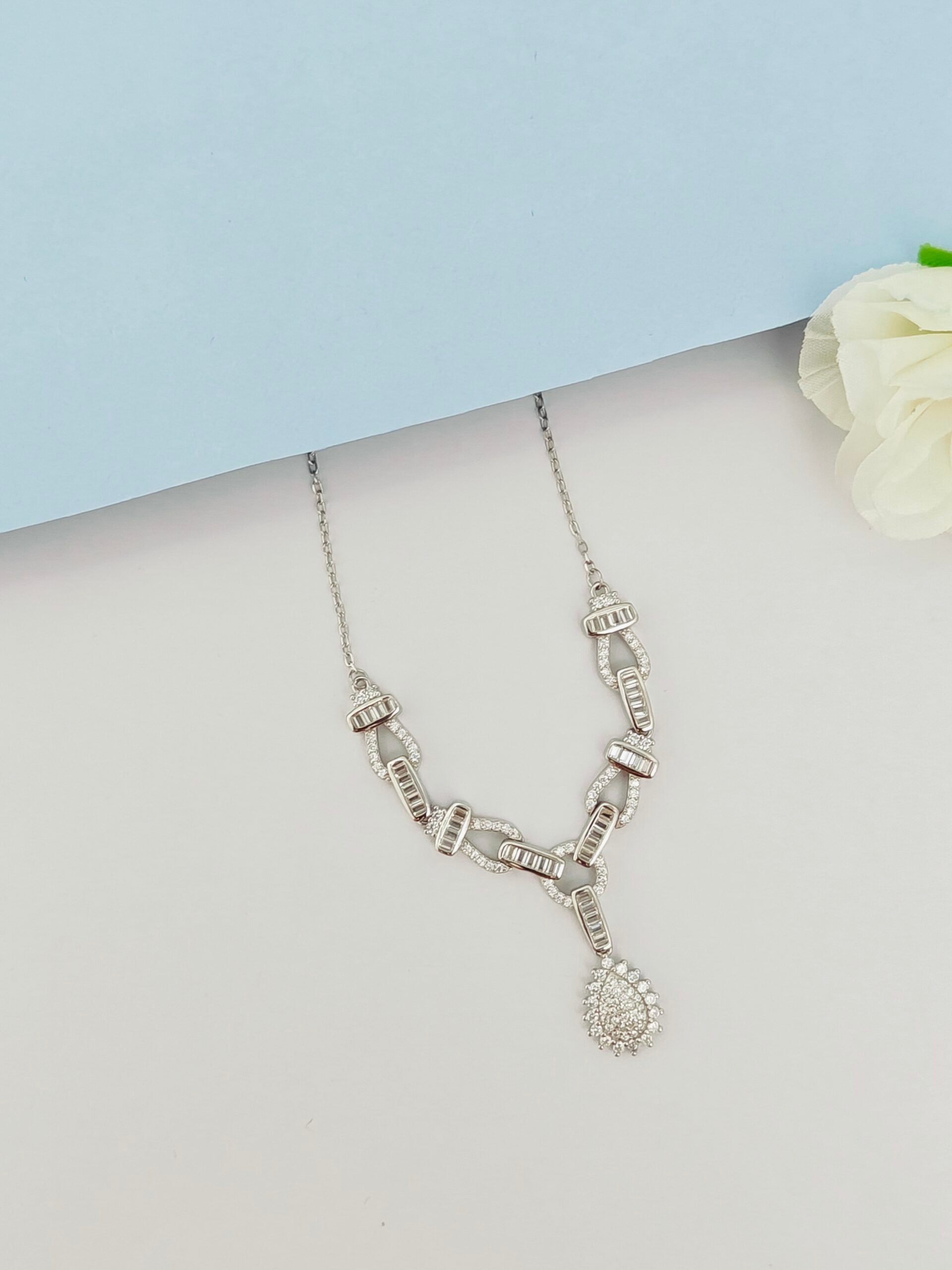 Silver necklace on a mannequin with a light blue background