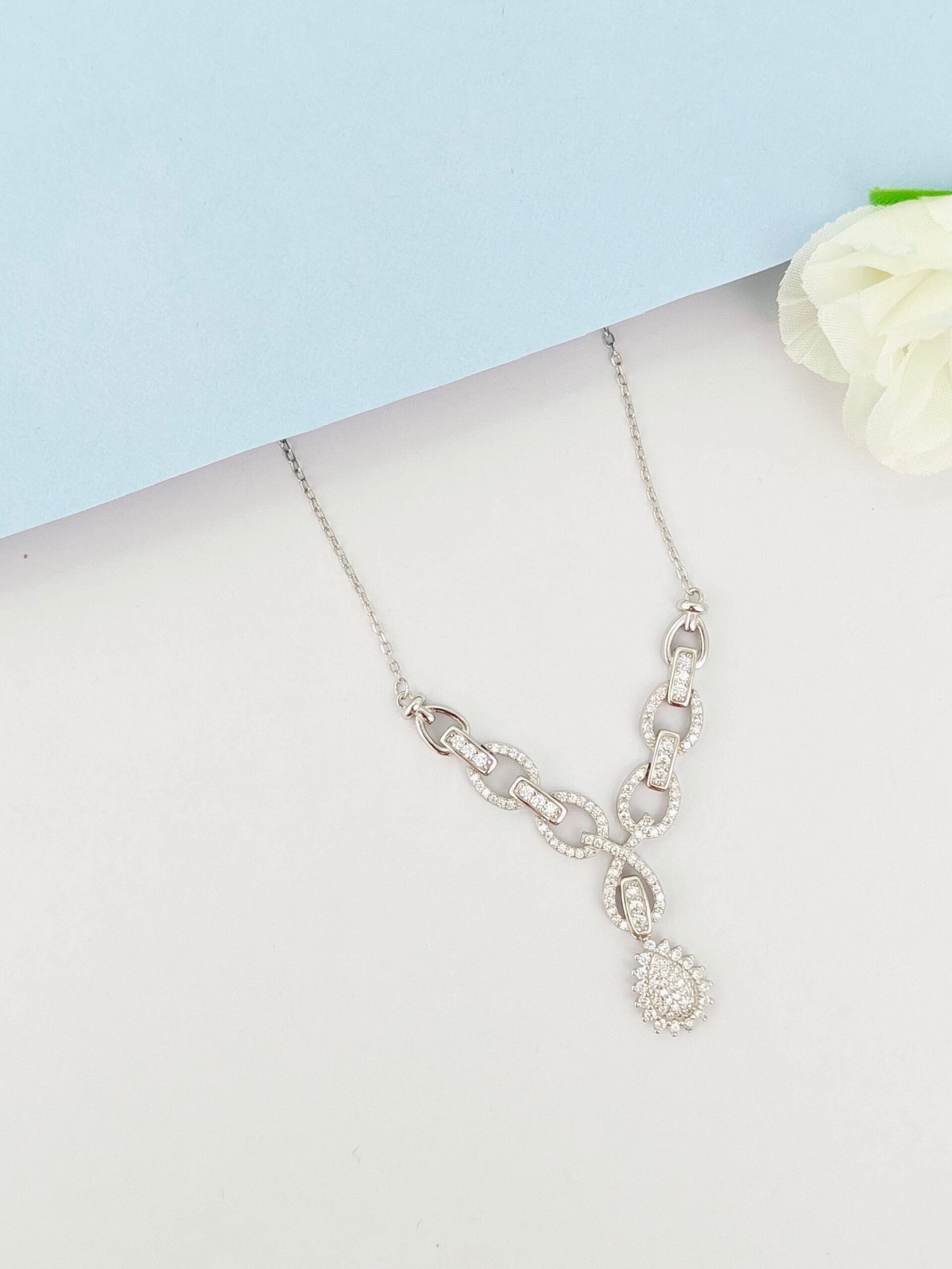 Silver necklace with a heart pendant on a mannequin bust against a light blue background.