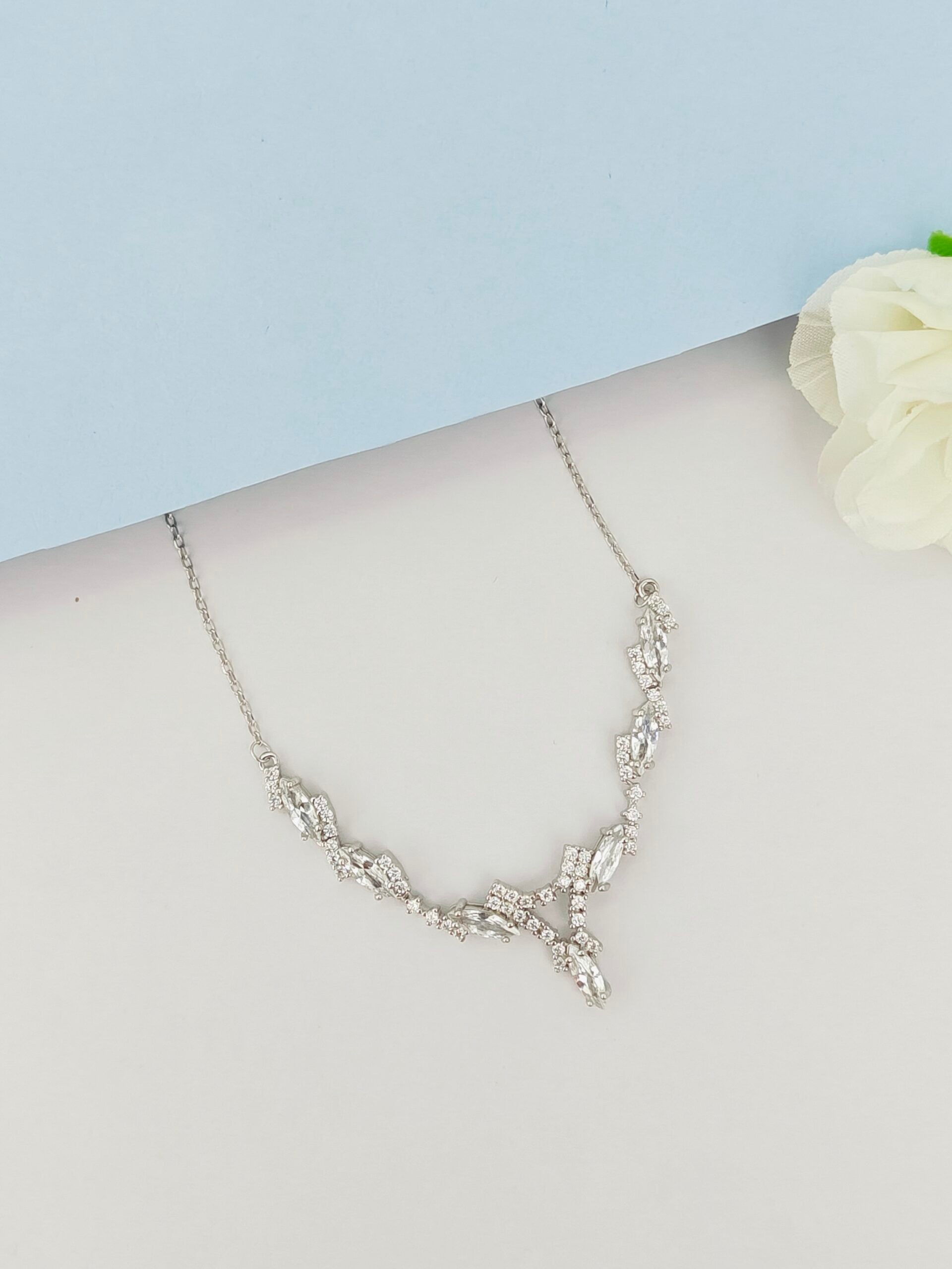 Silver necklace on a mannequin with a light blue background