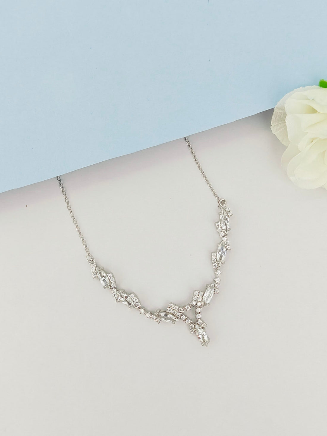 Silver necklace on a mannequin with a light blue background