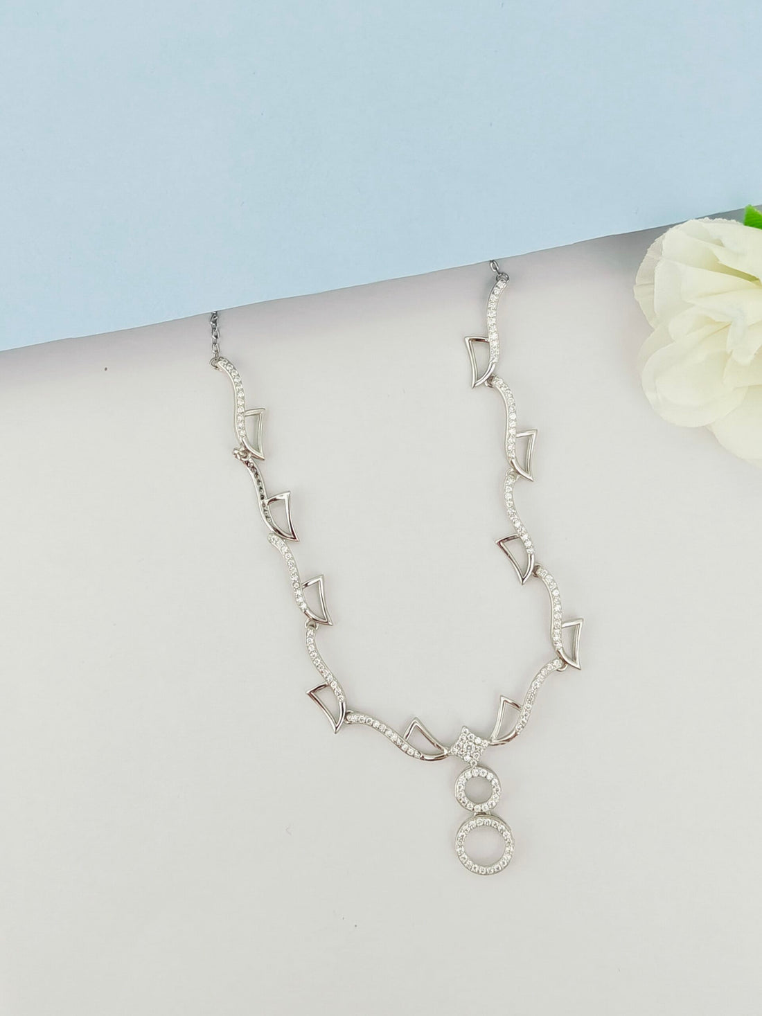 Silver necklace on a mannequin with a light blue background