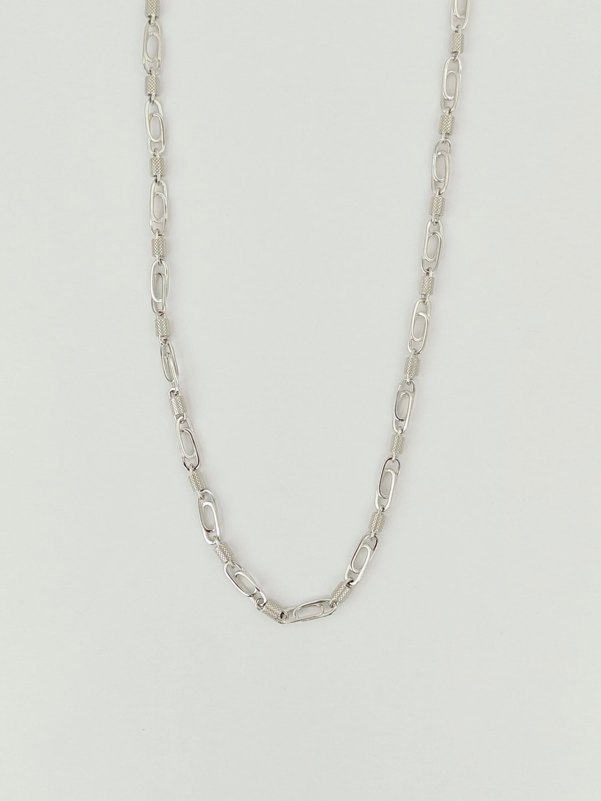 Silver chain necklace on a light gray background