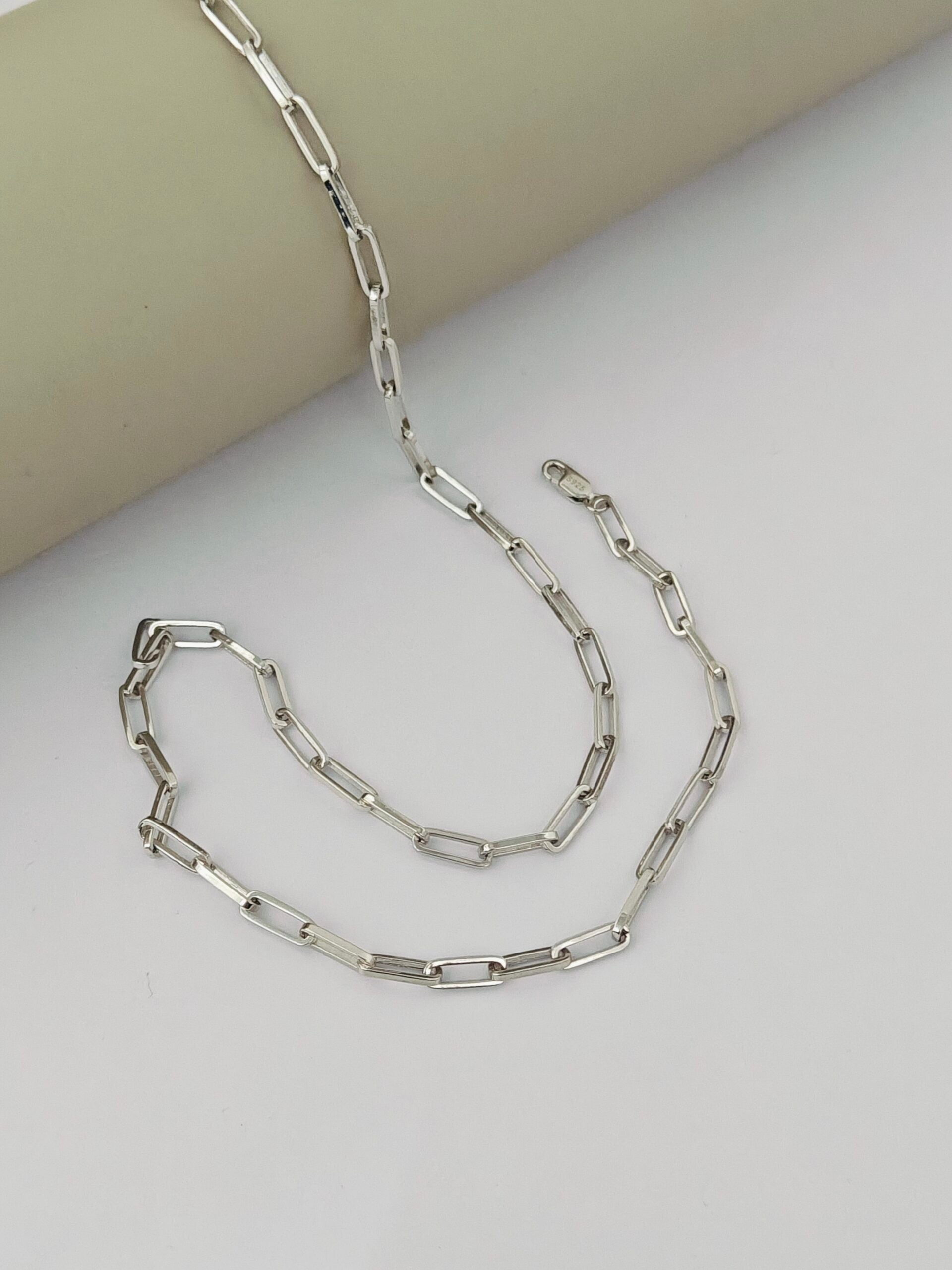 Silver chain necklace on a light gray surface