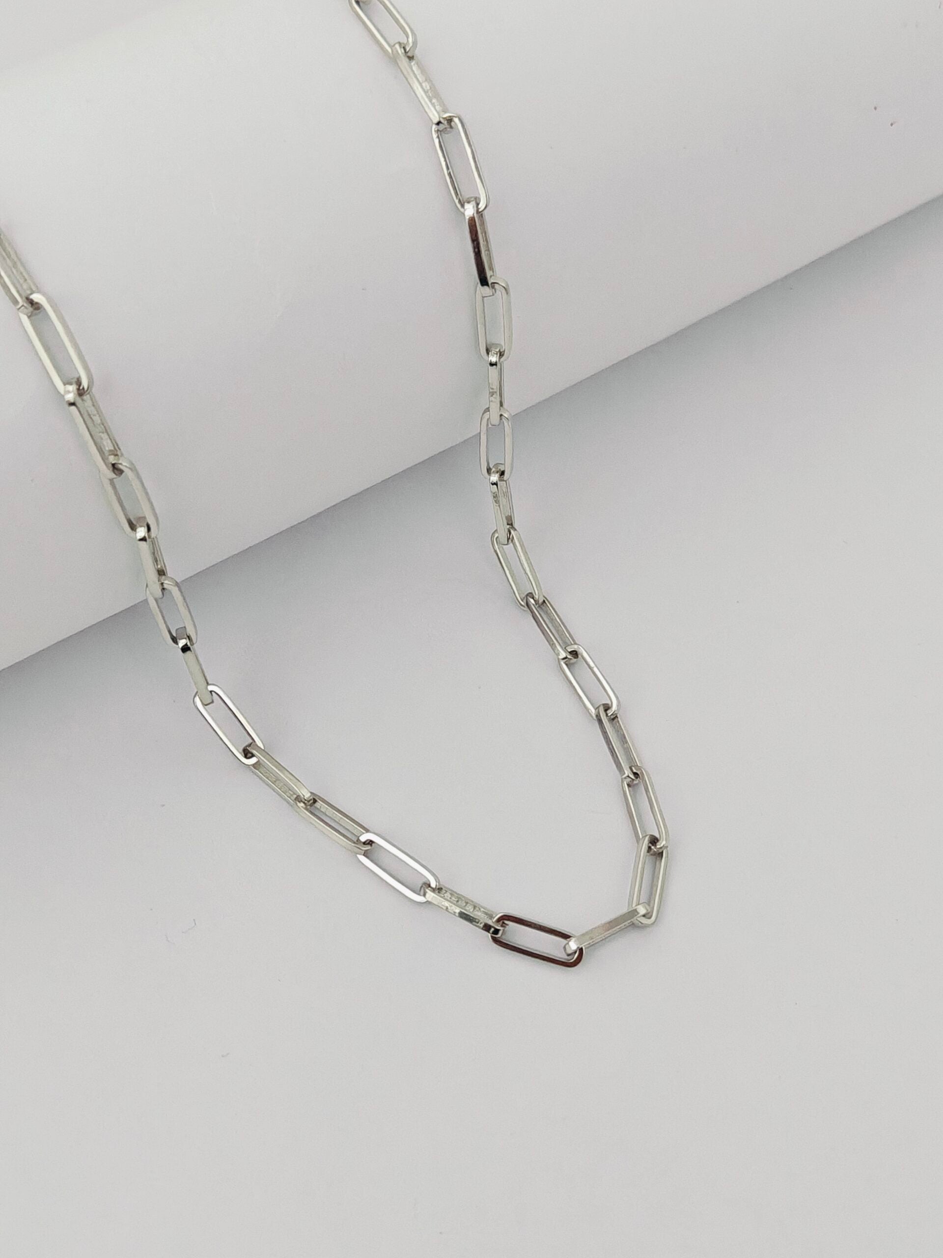 Silver chain necklace on a light gray background