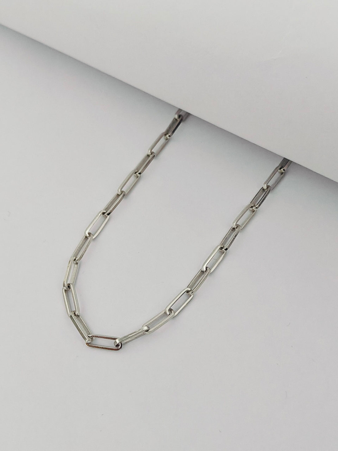 Silver chain necklace on a light gray background