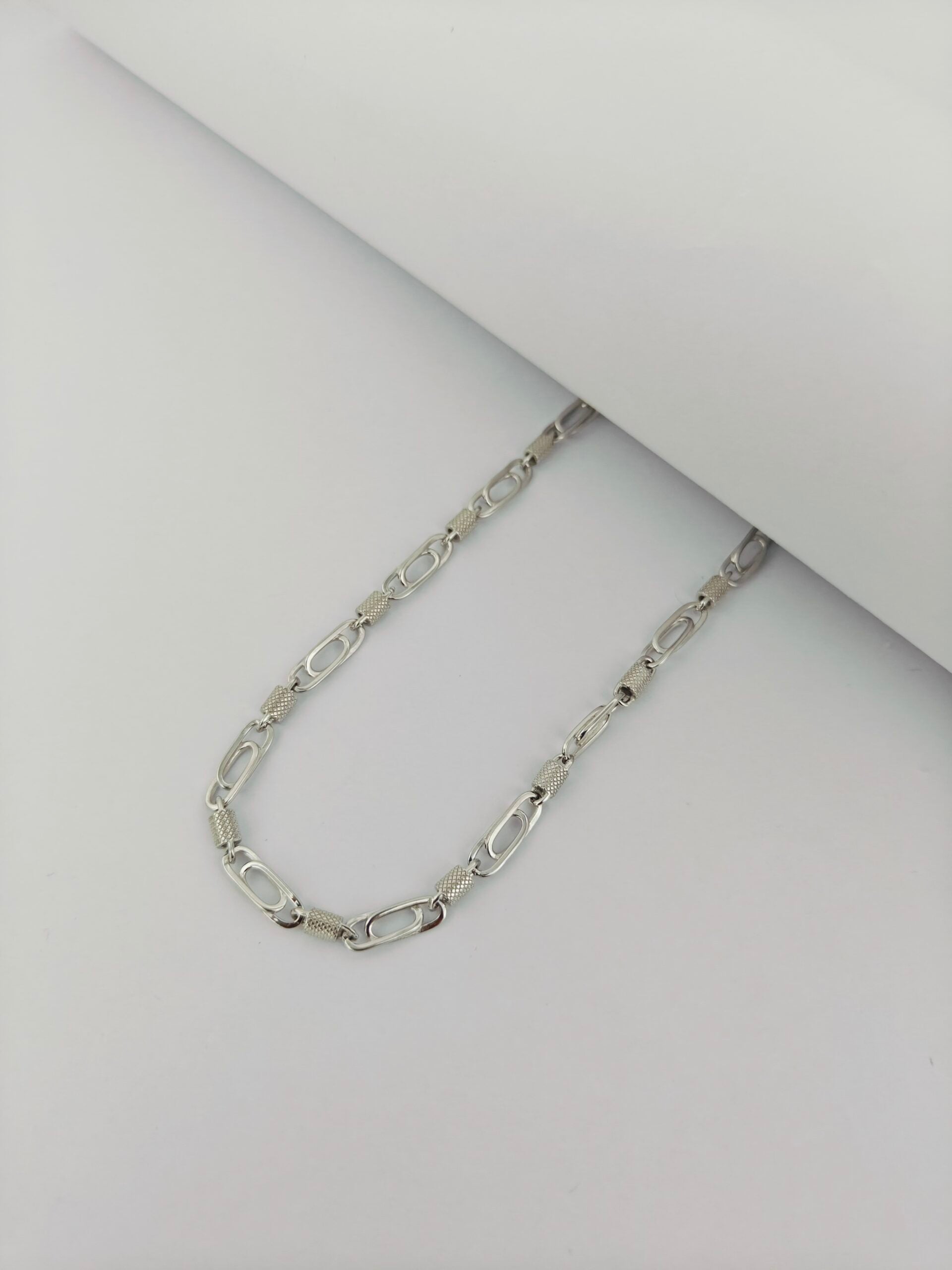 Silver chain necklace on a light gray background