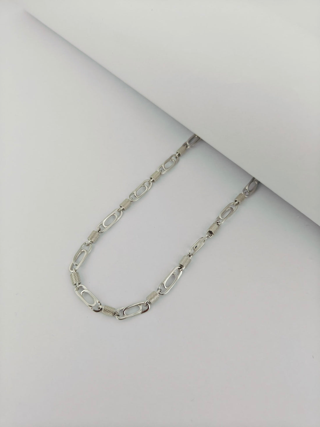 Silver chain necklace on a light gray background