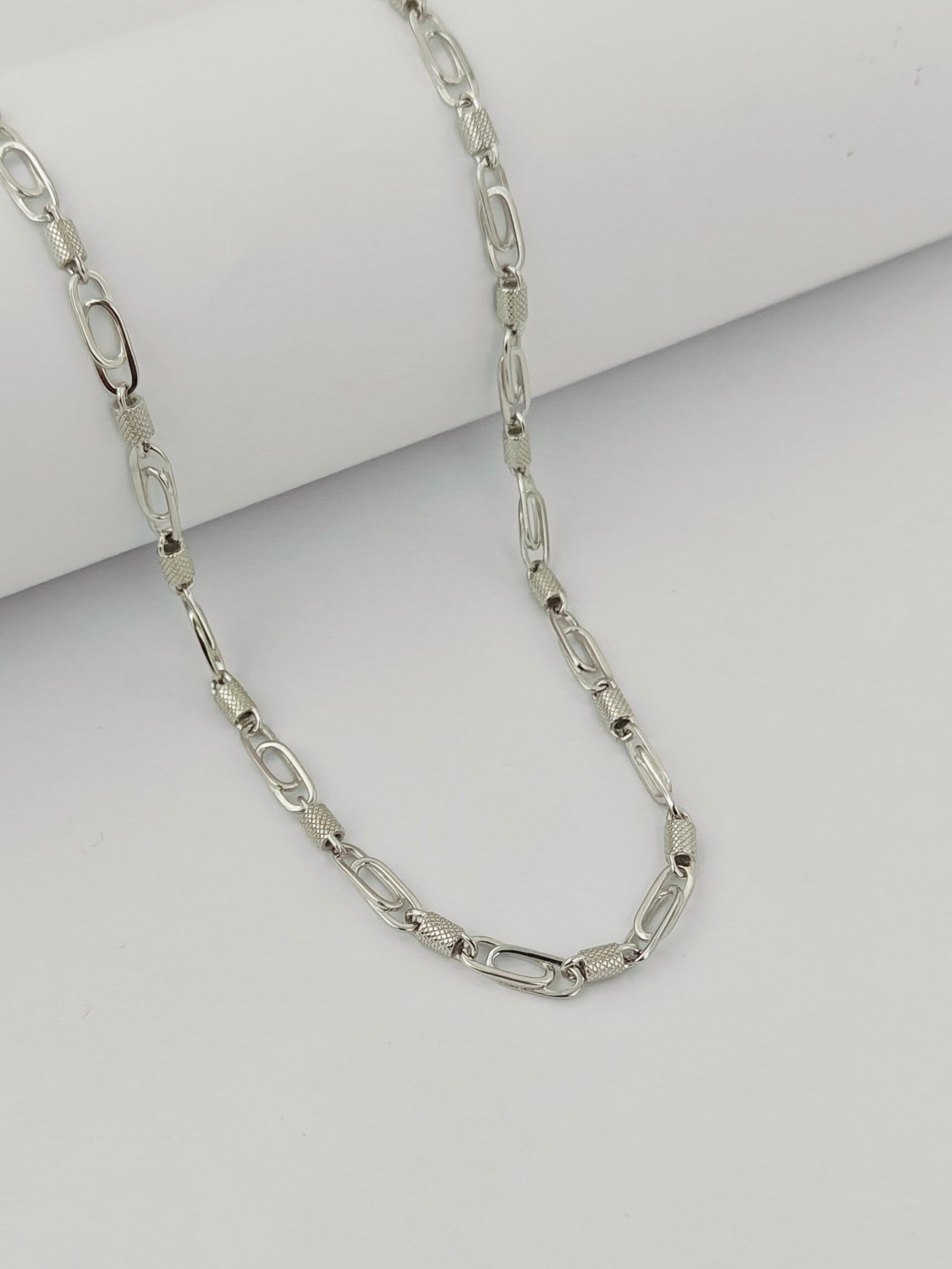 Silver chain necklace on a light gray background