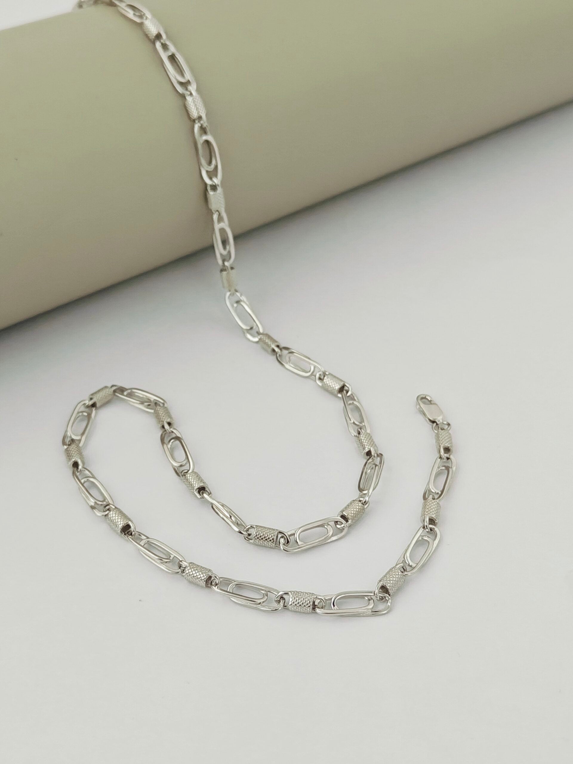 Silver chain necklace on a light beige surface