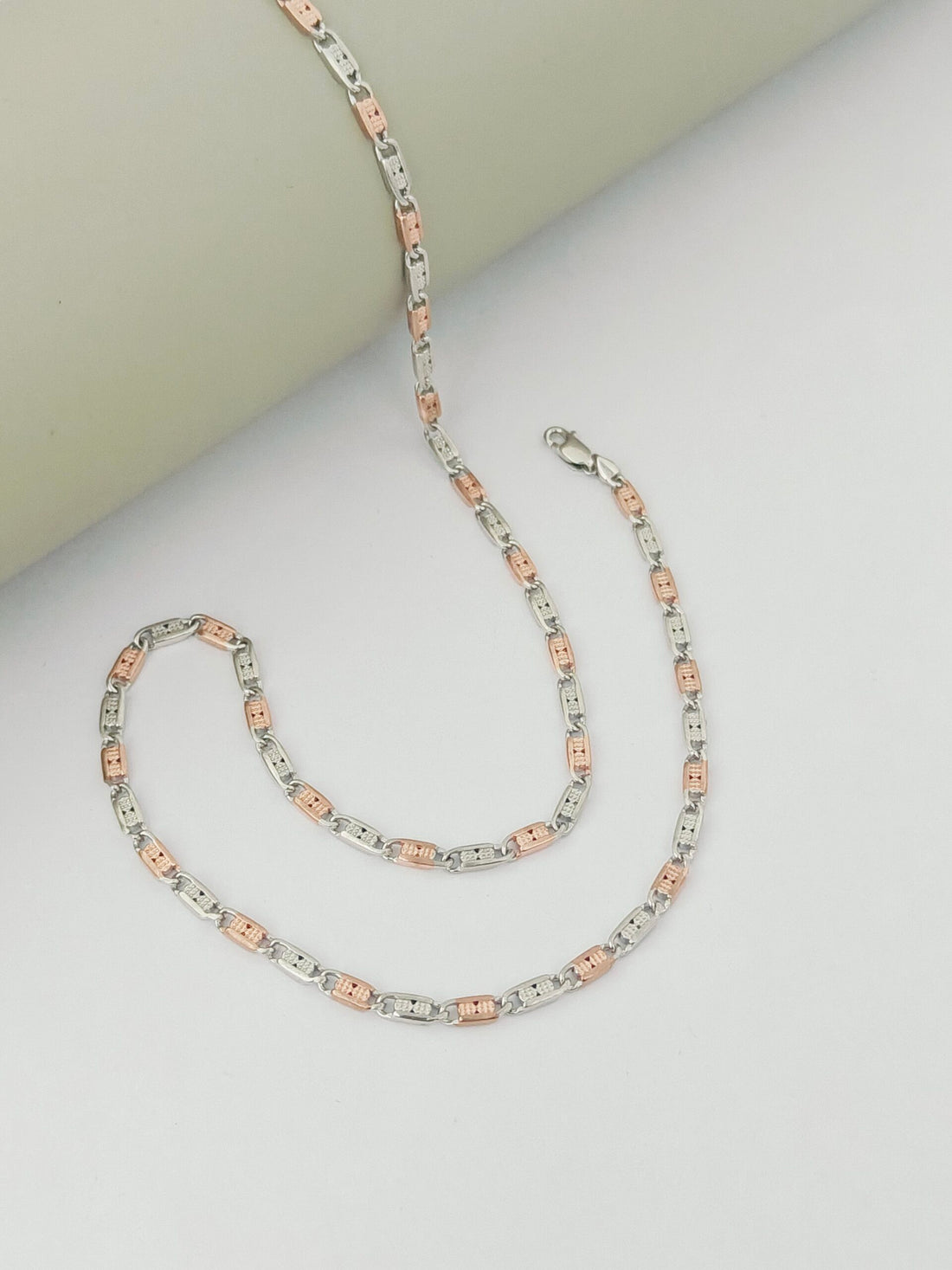 Two silver chains with pink accents on a light gray background